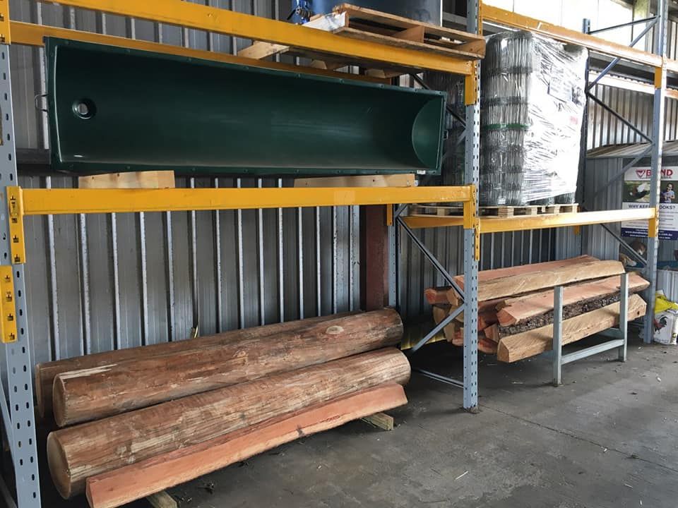 A Warehouse Filled With Wooden Logs And A Green Trough — Maleny Hardware & Rural Supplies In Maleny, QLD