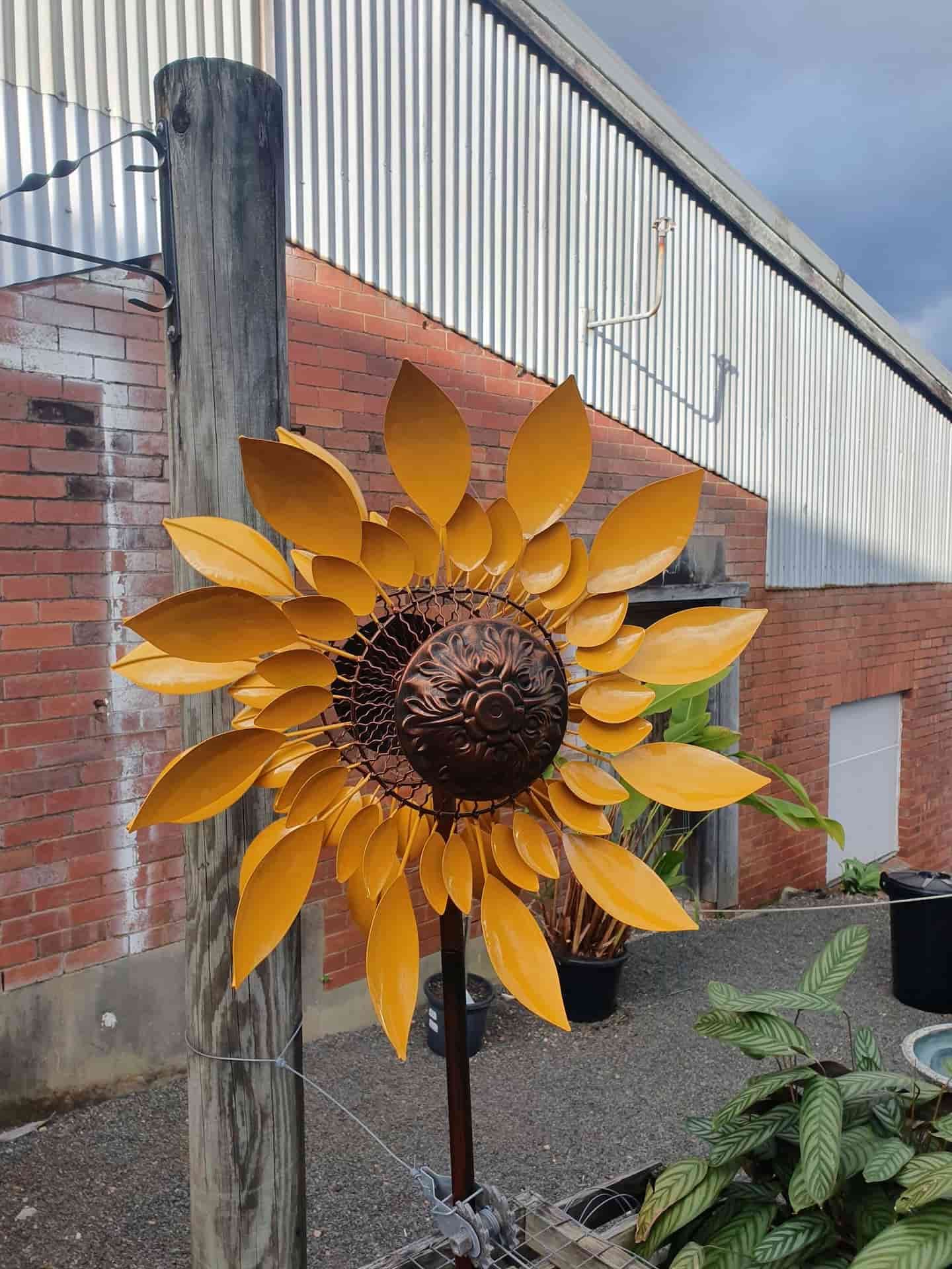 A Large Metal Sunflower Is Sitting On A Wooden Post — Maleny Hardware & Rural Supplies In Sunshine Coast, QLD