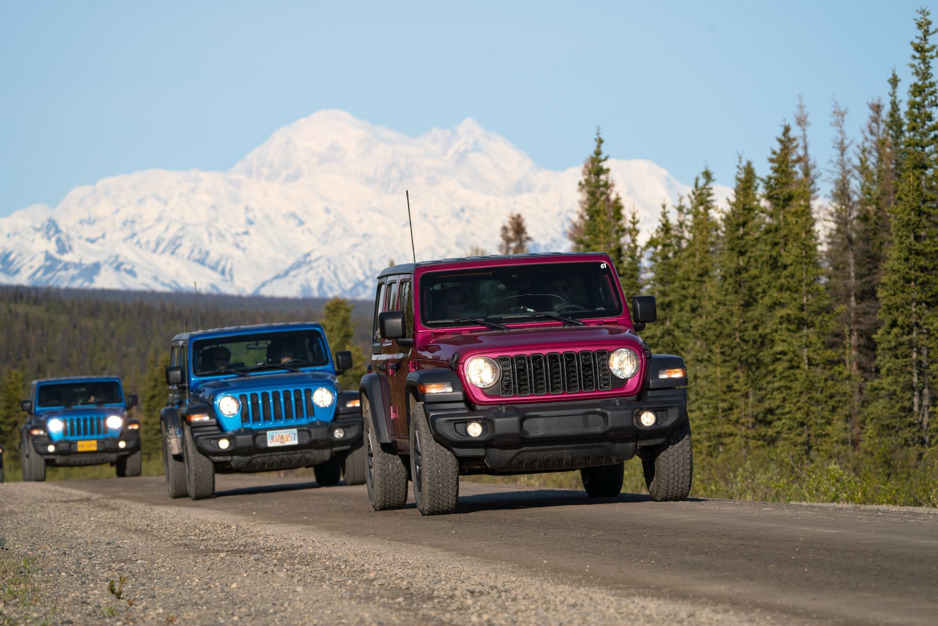 Three off-road jeeps driving on a road