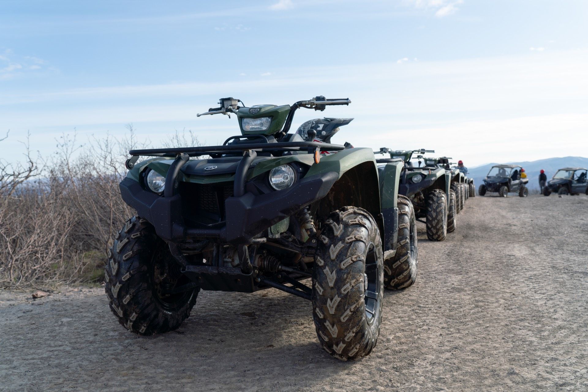 Row of parked all-terrain vehicles on a gravel road in a rural landscape
