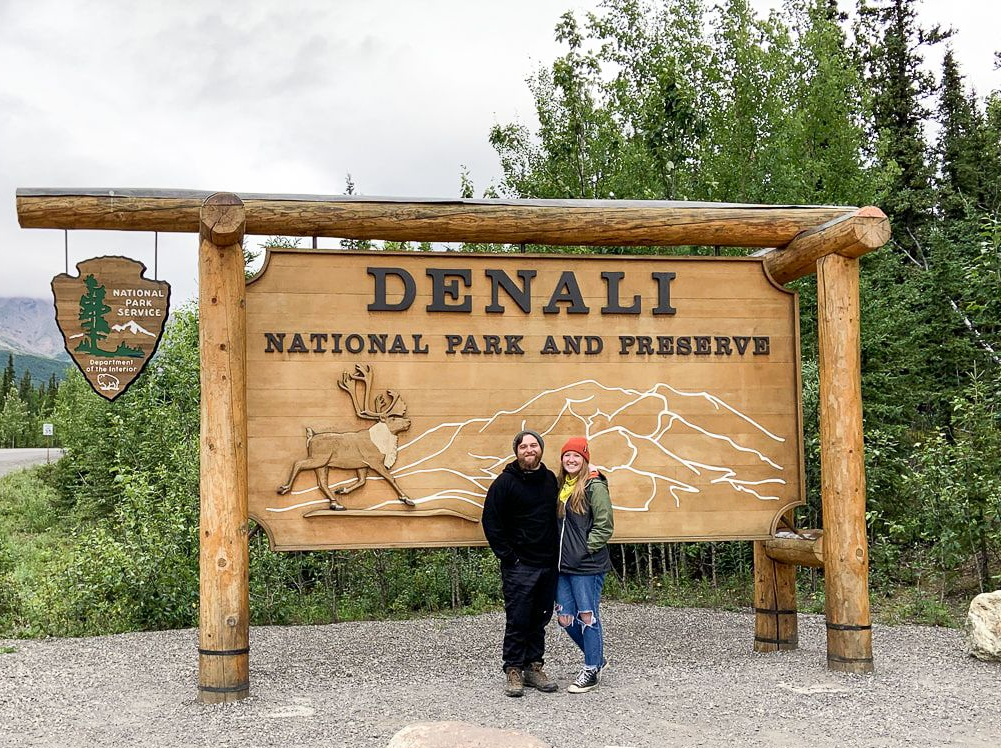 People posing in front of the Denali National Park and Preserve sign.