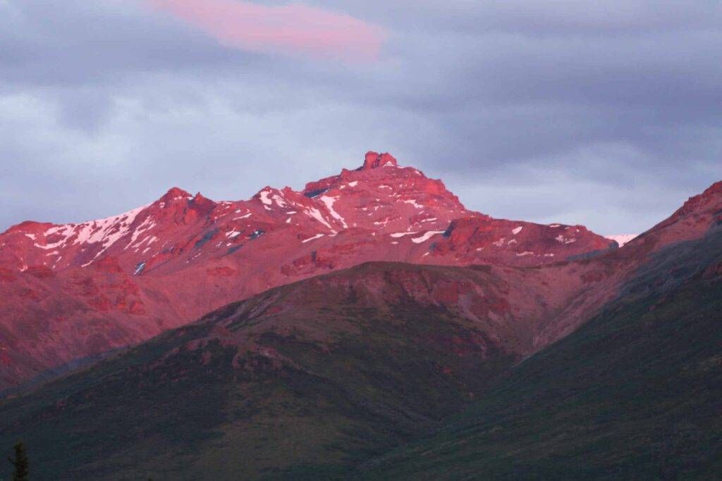 Pink-lit mountain ridge under cloudy dusk sky