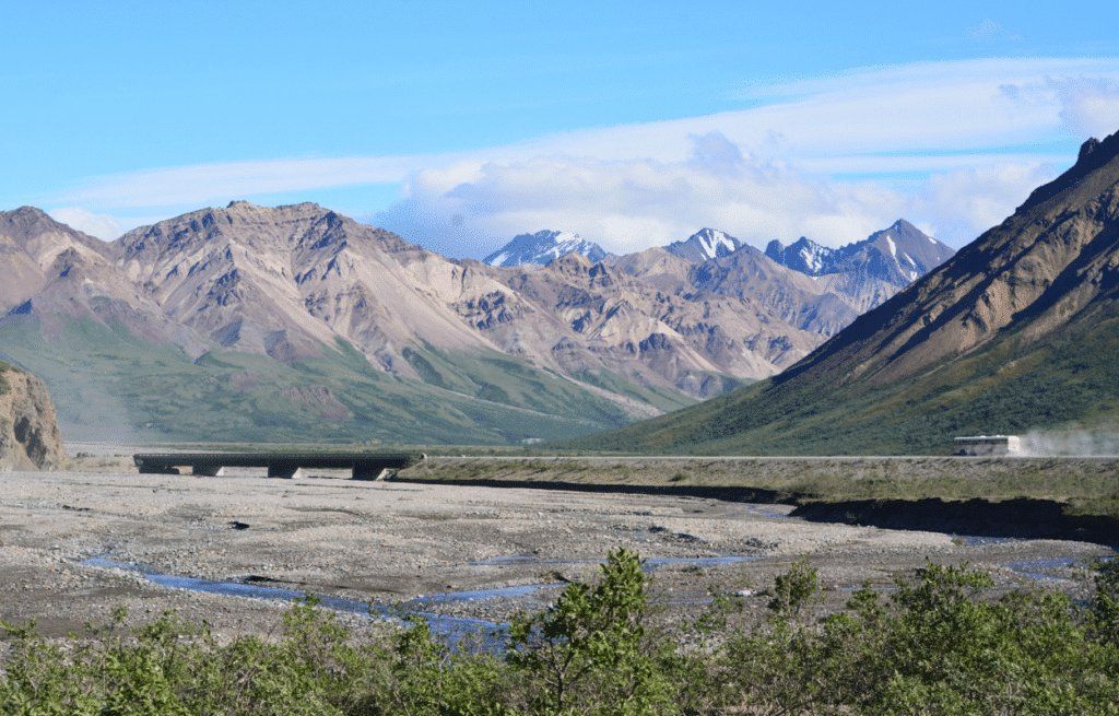 Rocky mountain range above a wide gray riverbed under a clear blue sky