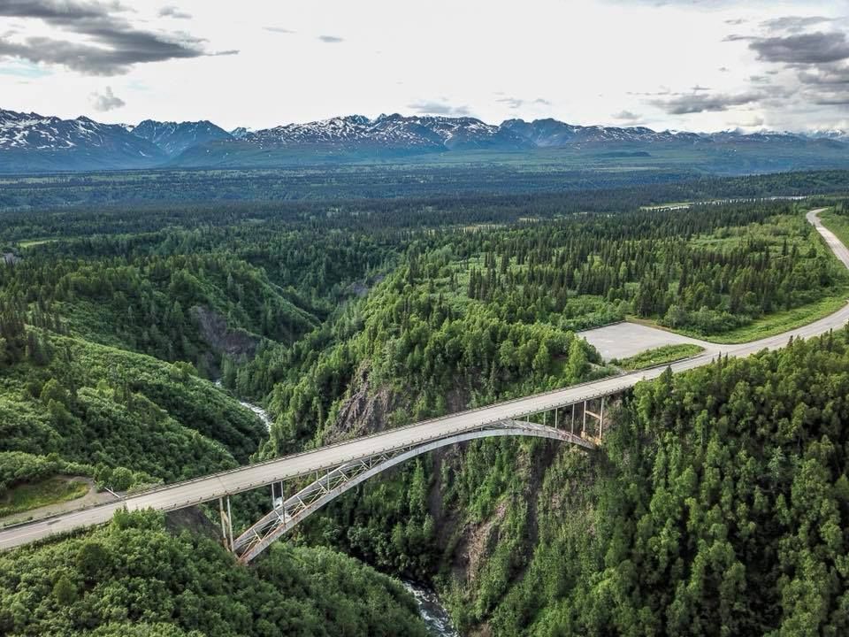 High bridge crossing a green forested valley with mountains in the distance