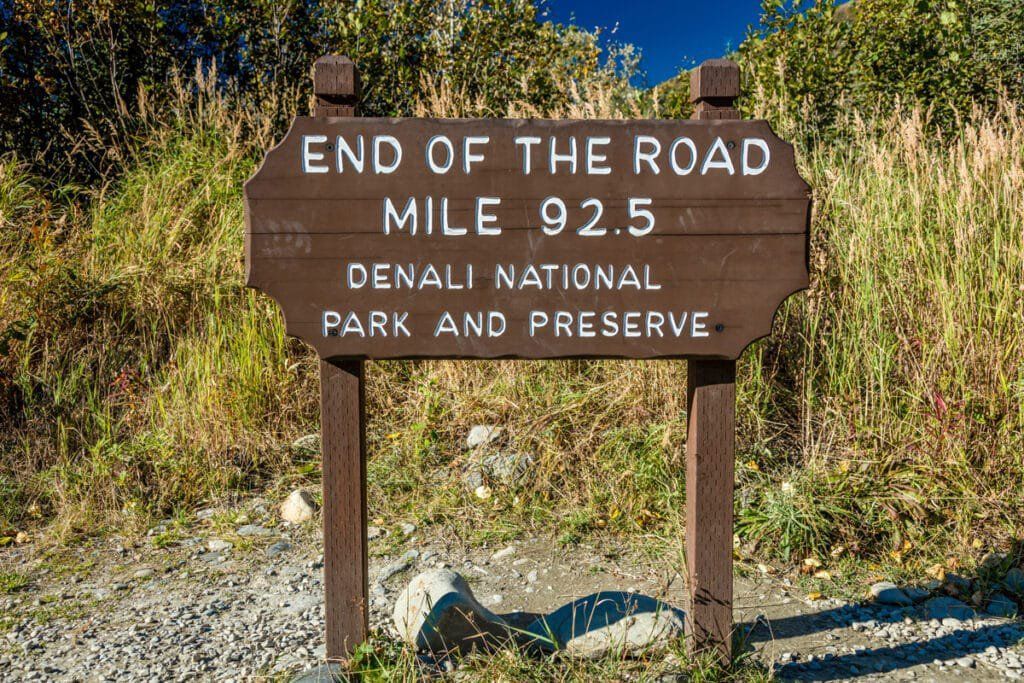 Wooden “End of the Road” sign for Mile 92.5 in Denali National Park and Preserve, beside a gravel road