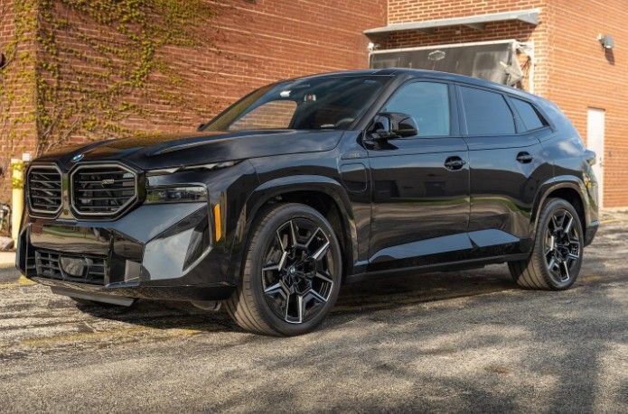Black BMW SUV parked beside a brick building on a sunny day