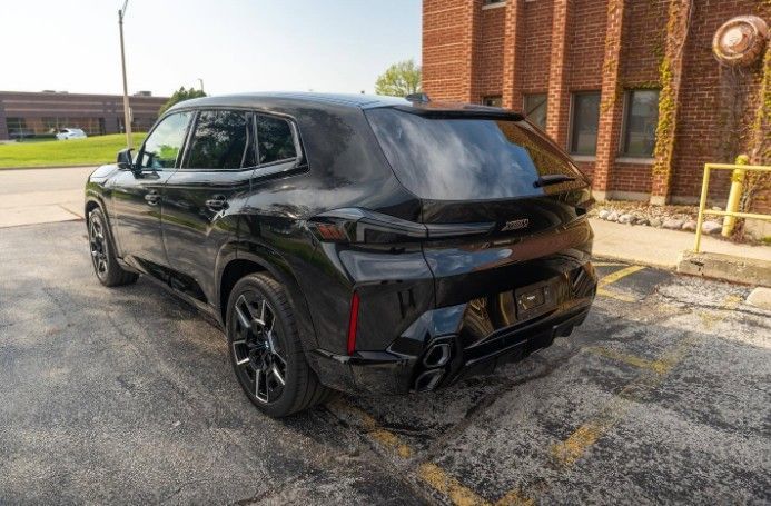 Black SUV parked beside a brick building in a sunlit lot