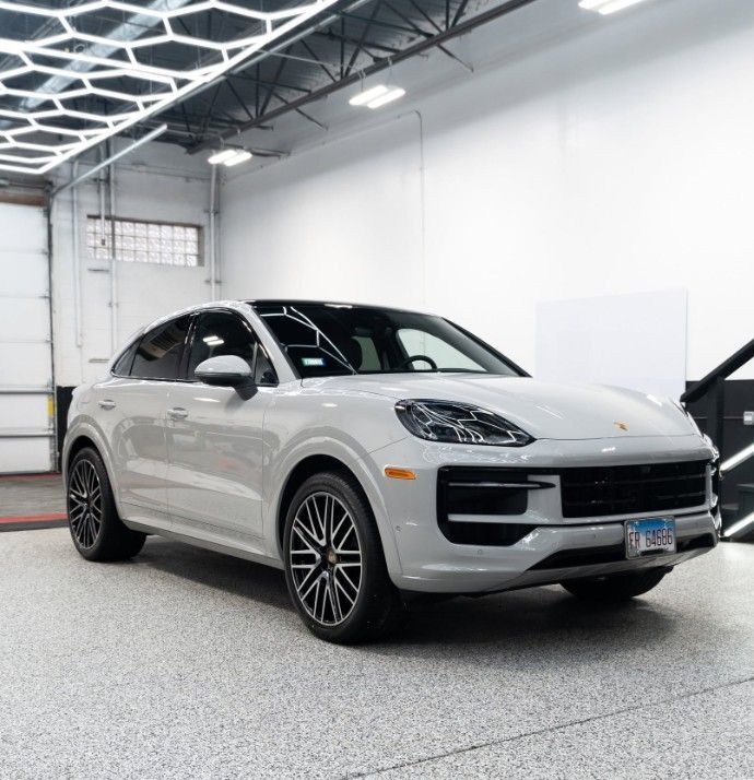 White Porsche SUV parked in a bright indoor garage with a glossy floor