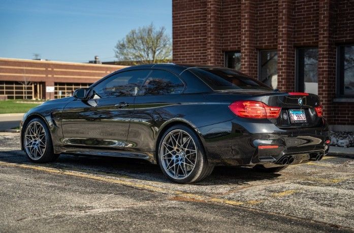 Black BMW coupe parked outside a brick building on a sunny day