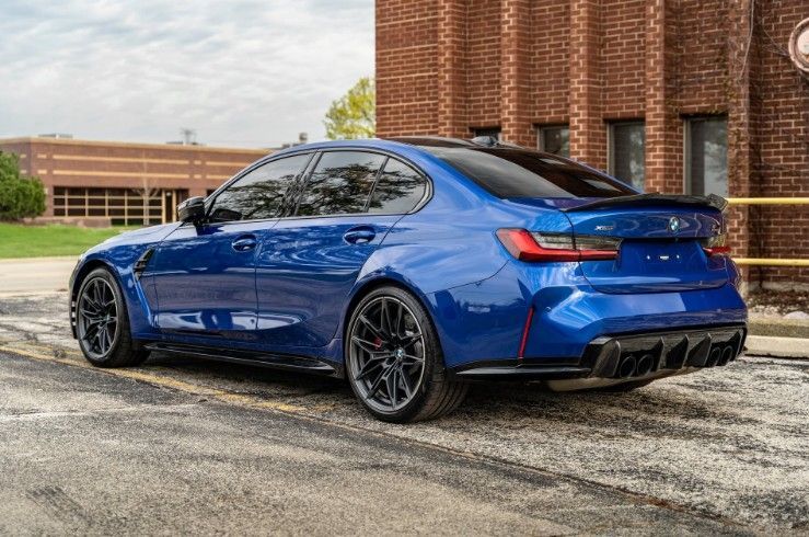 Blue sports sedan parked outside a brick building on a paved lot
