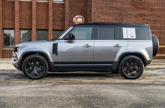 Silver and black SUV parked beside a brick building on a wet street