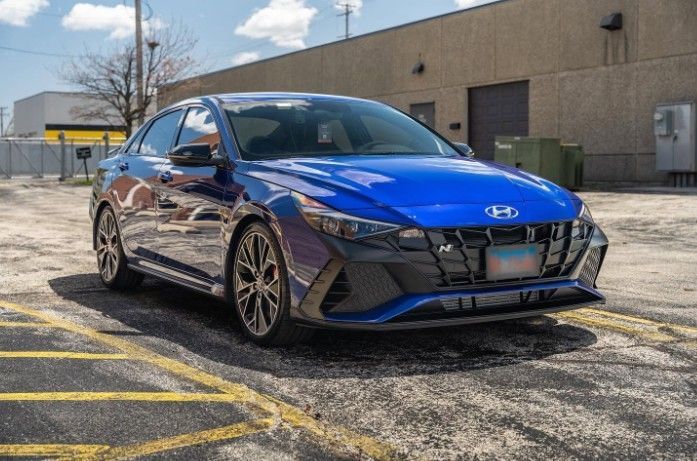 Blue Hyundai sedan parked in an industrial lot under a partly cloudy sky