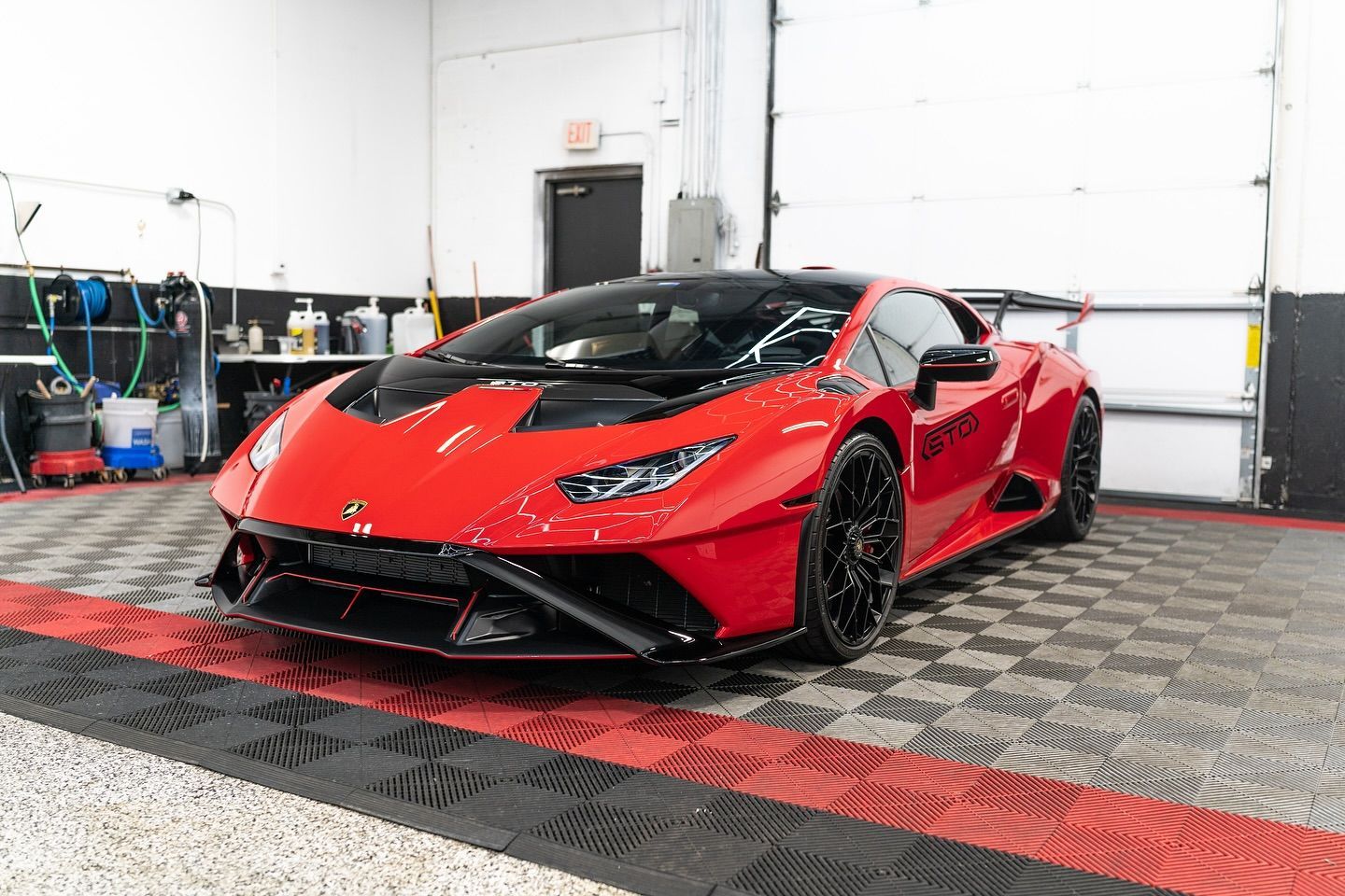 Red Lamborghini sports car in a garage, viewed from the front at an angle.