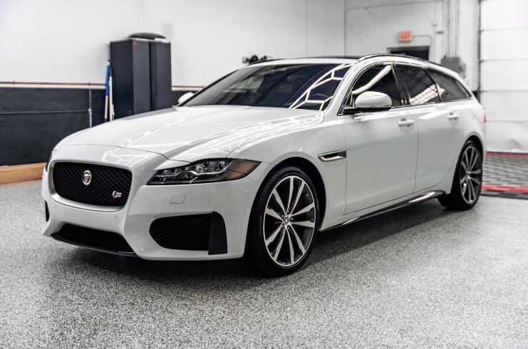 White Jaguar wagon parked indoors on a showroom floor, front-left view