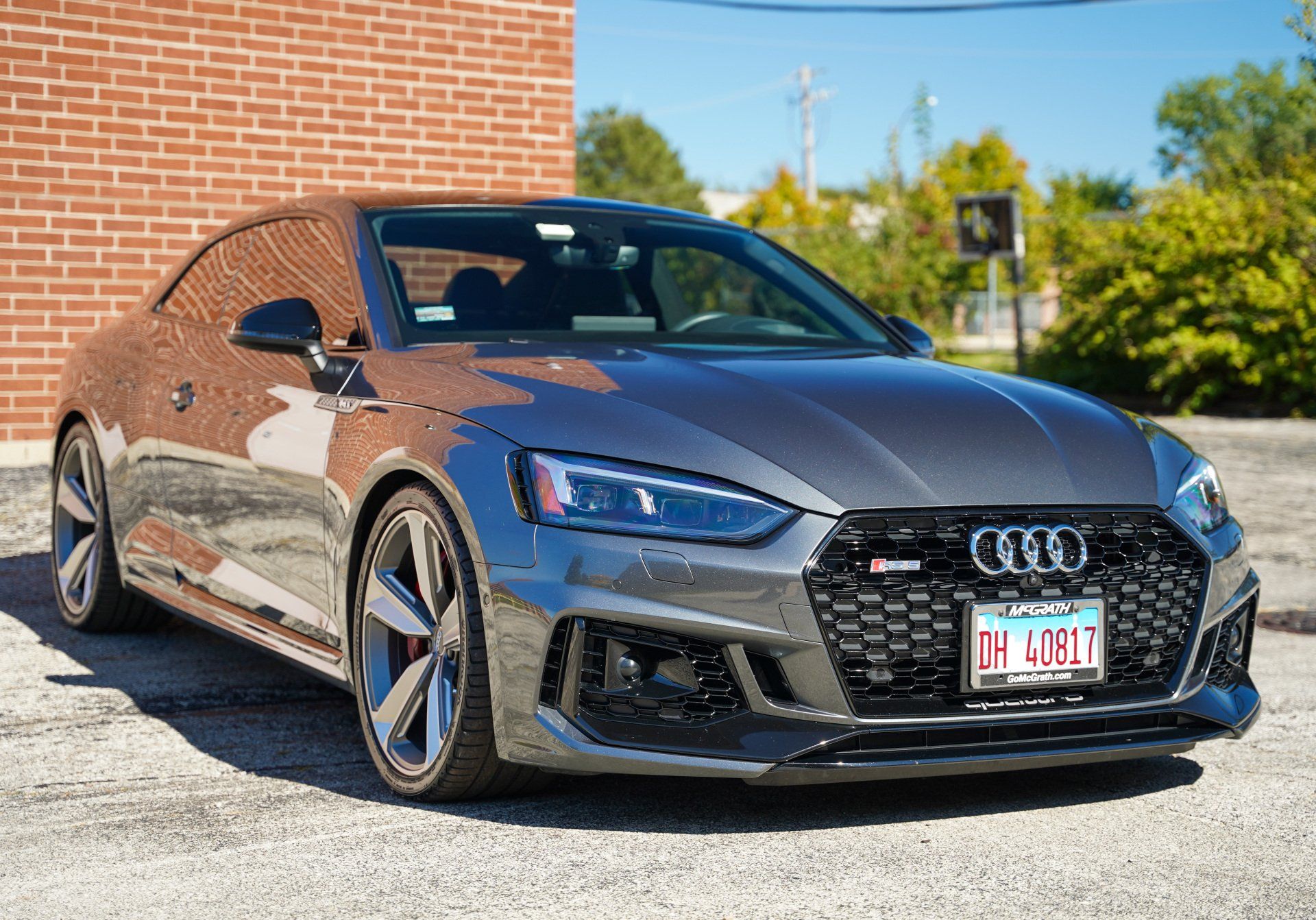 A gray audi rs 5 coupe is parked in front of a brick building.