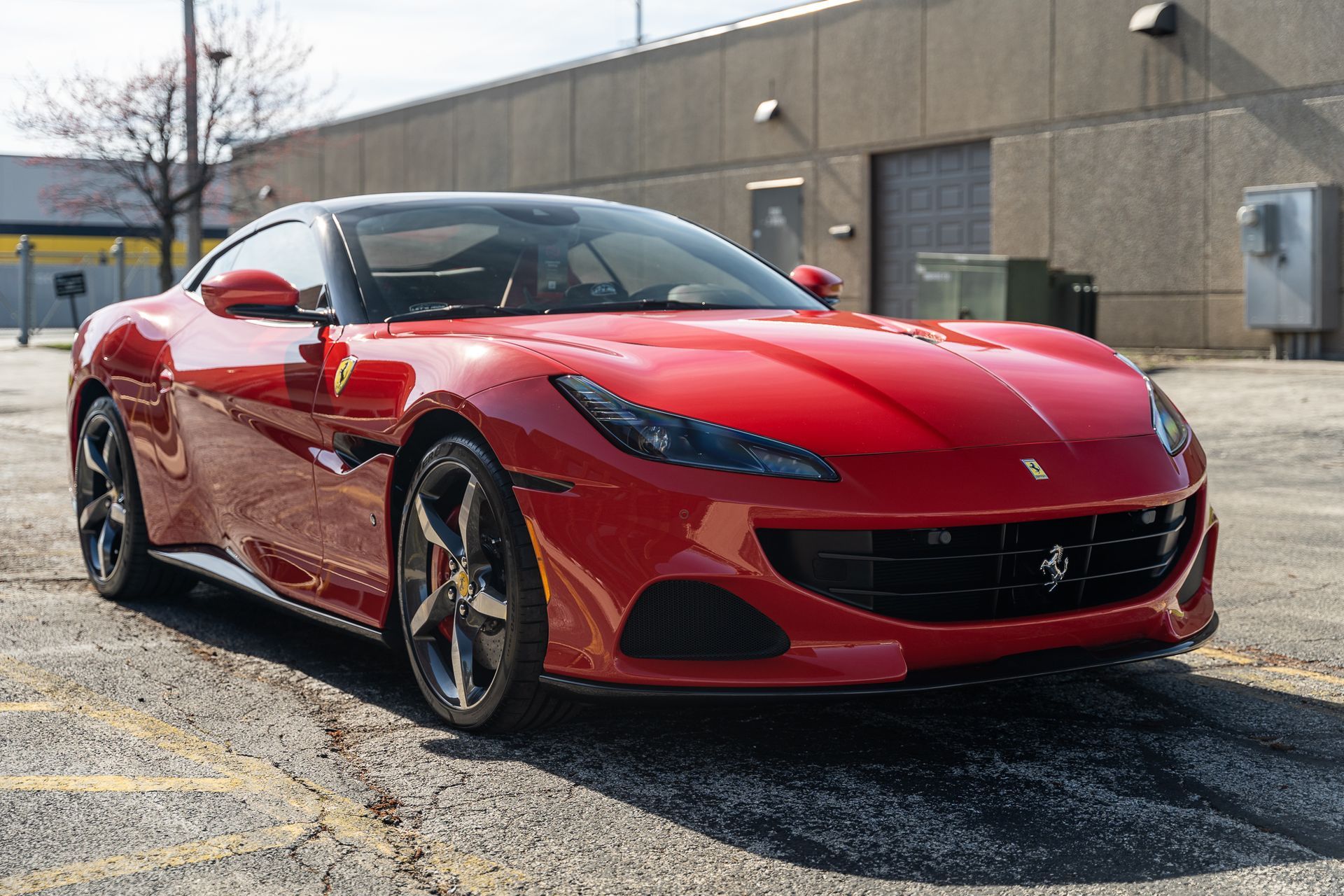 Red Ferrari sports car parked outside, sleek design, dark roof.