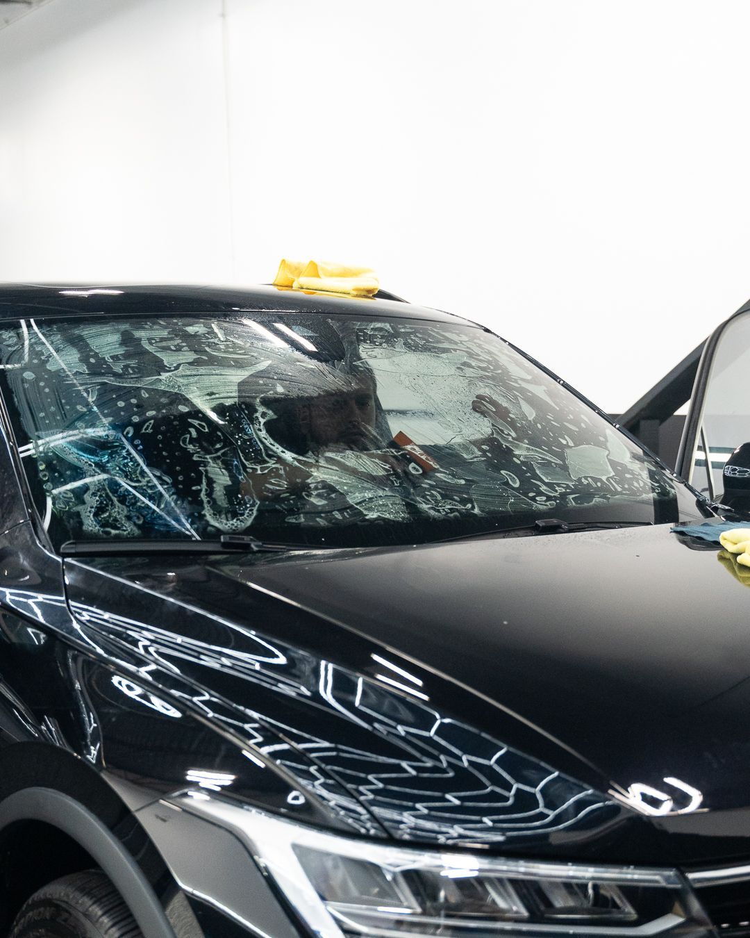 Black SUV with shattered windshield and a smashed side window, parked with the front passenger door open.