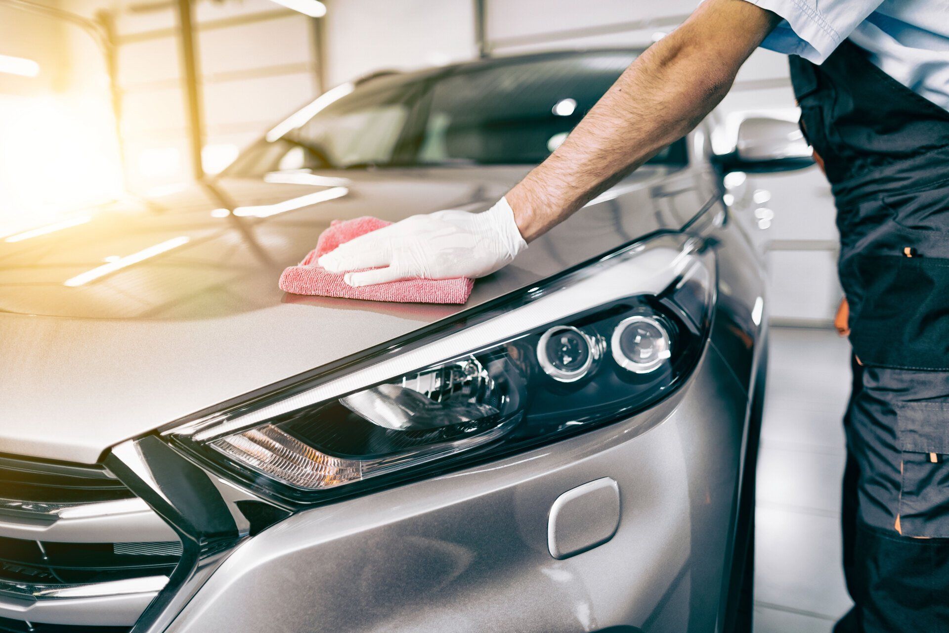 A man is cleaning a car with a towel in a garage.