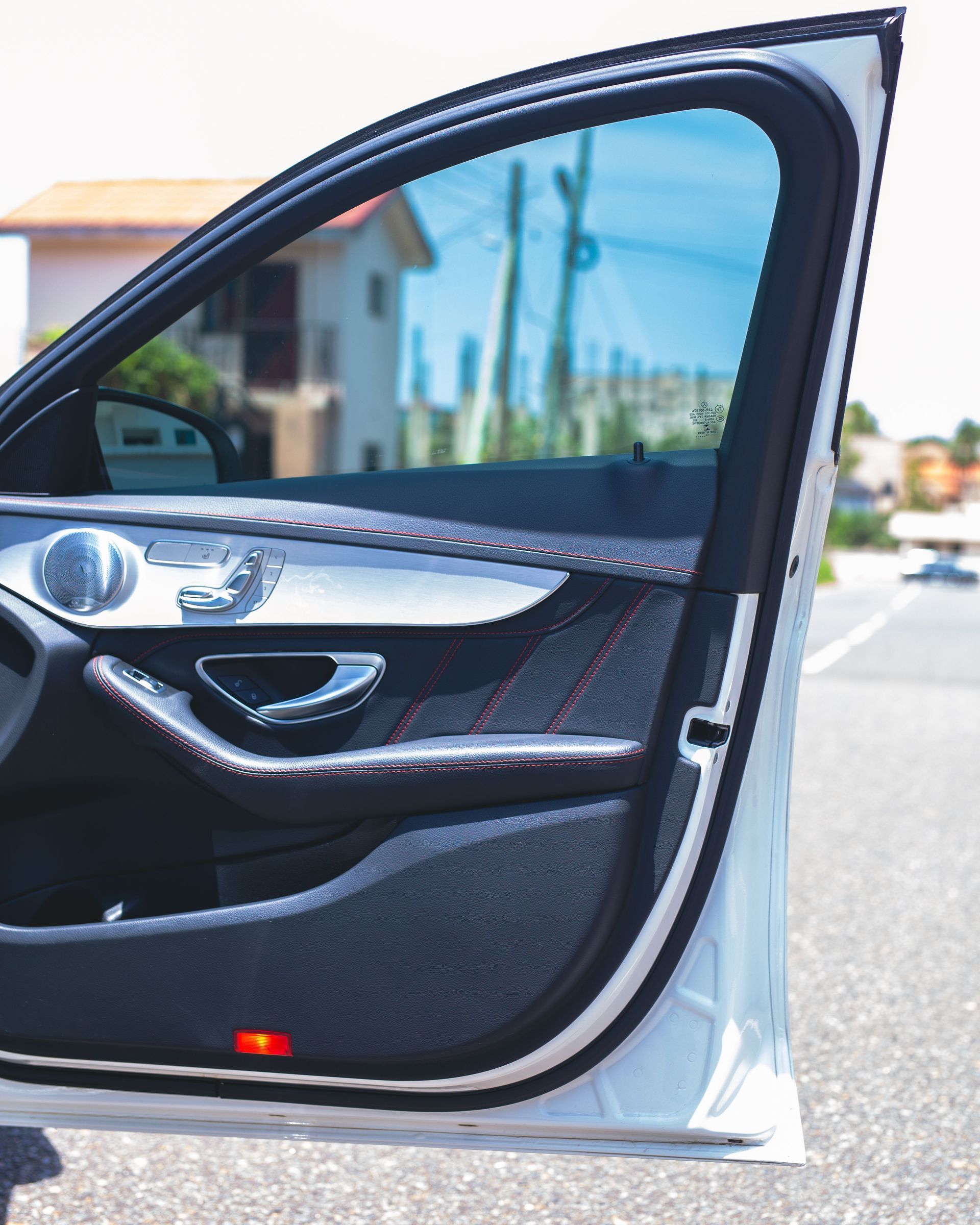 Open car door showing black interior and silver trim on a sunny street