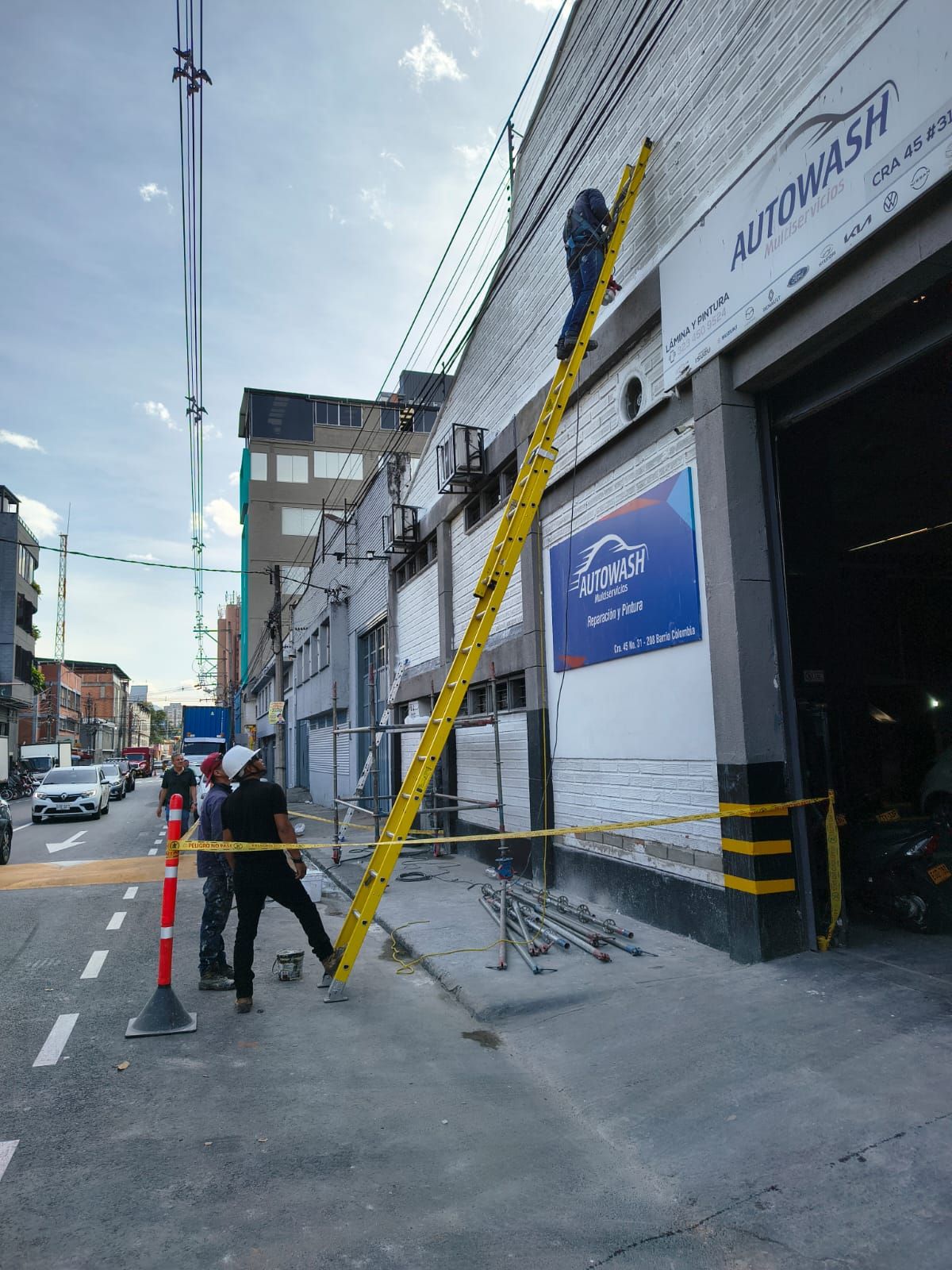 Trabajadores pintando la pared exterior de una casa en un día soleado.