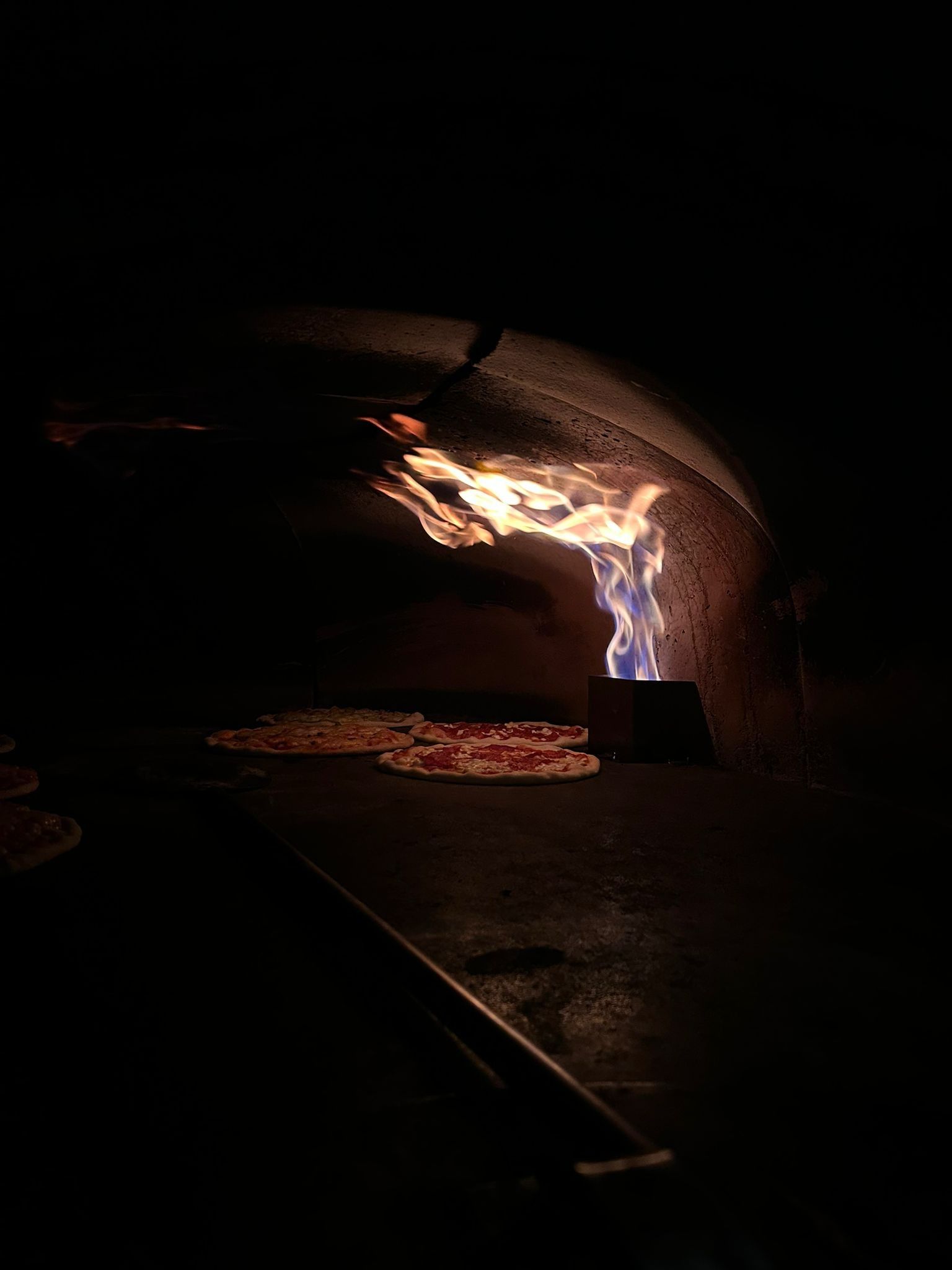 Tre pizze su piatti bianchi, due con condimenti, su una tovaglia color crema.