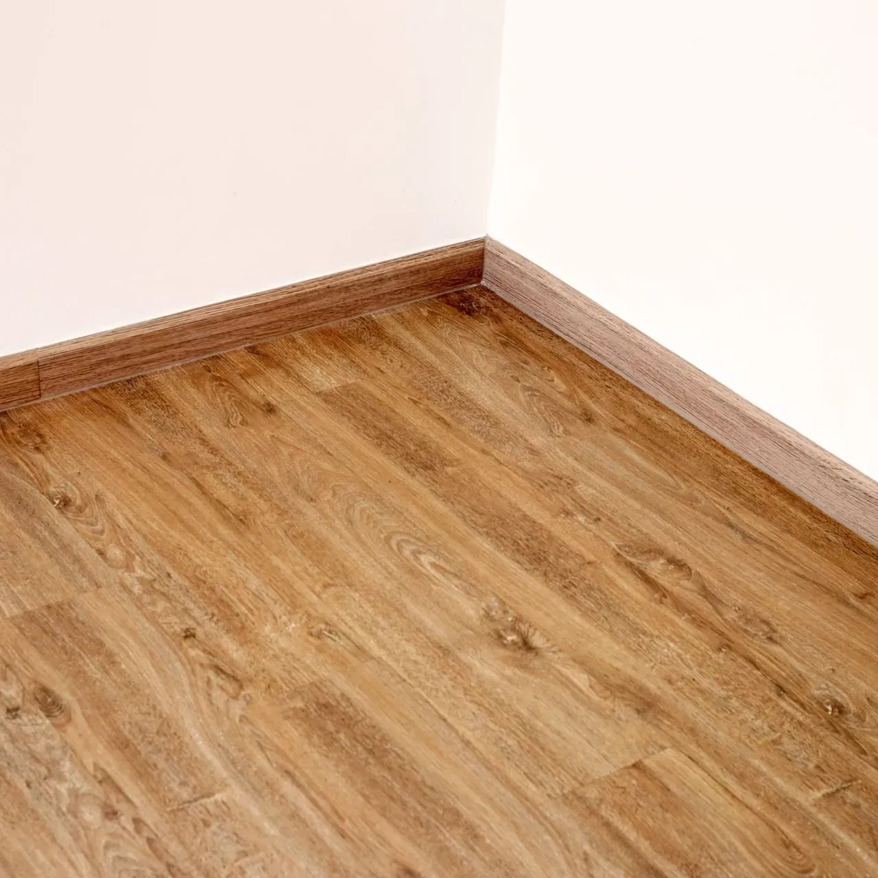 Empty room corner with light wood flooring and white walls
