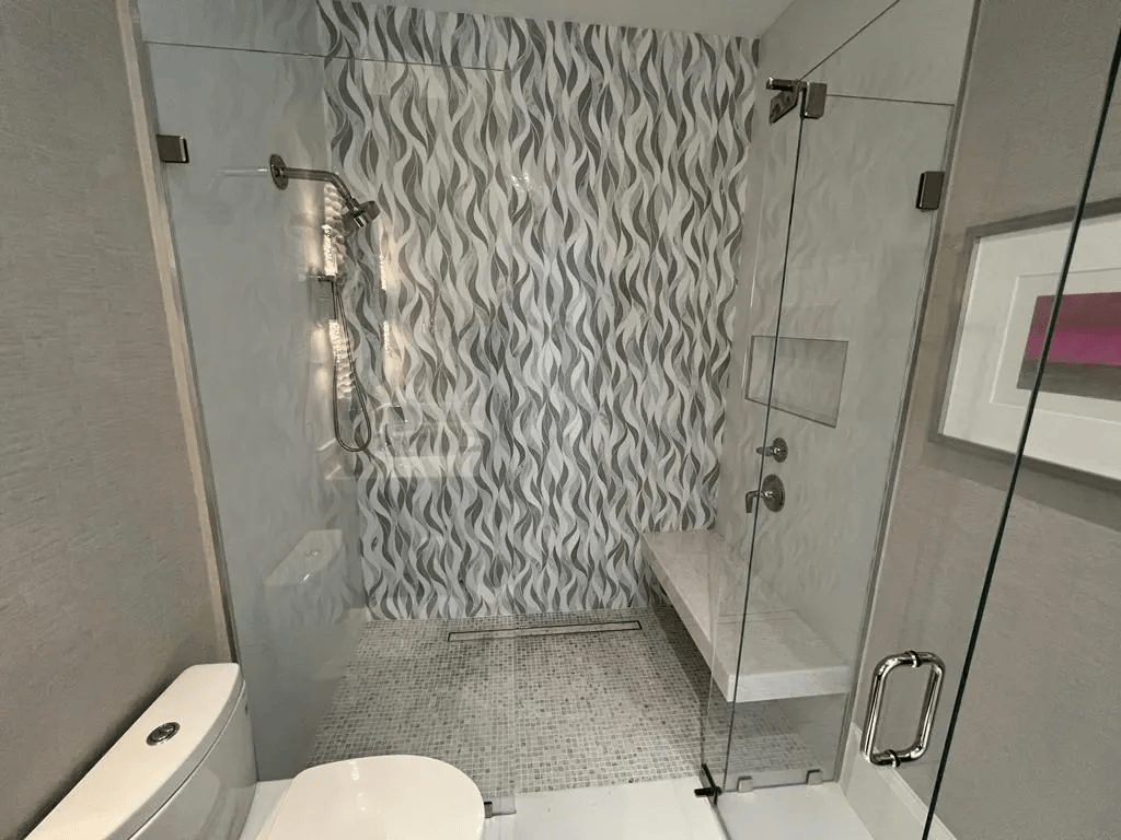 Modern bathroom with glass shower, white vanity, and gray patterned shower curtain