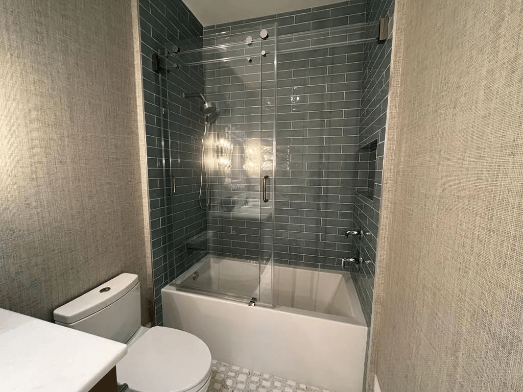 Small bathroom with toilet and tub shower tiled in dark gray.