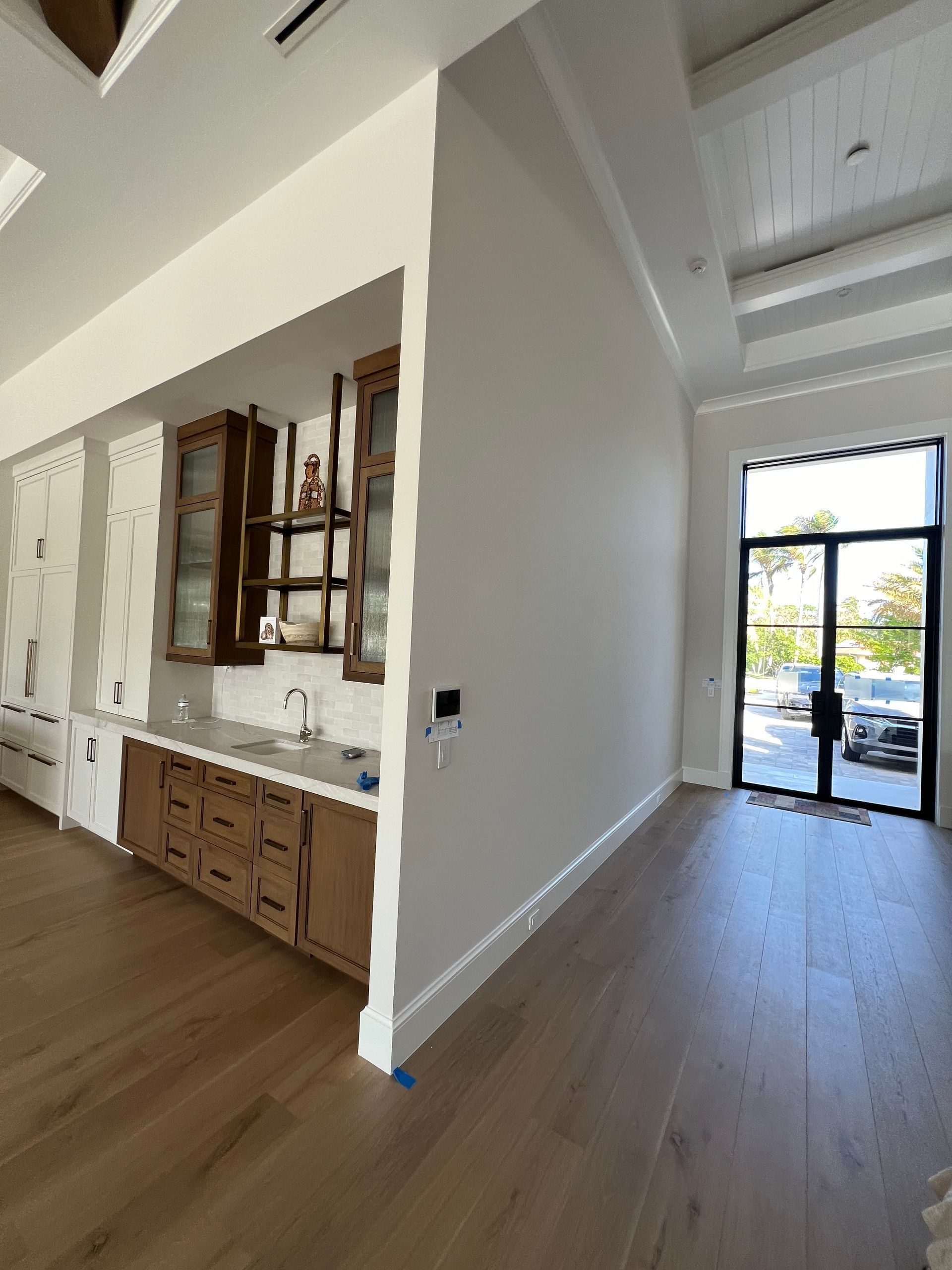 Bright modern room with wood floors, built-in cabinets, and glass front door looking outside