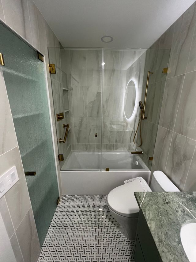 Modern bathroom with glass shower, floating vanity, toilet, and mosaic tile floor