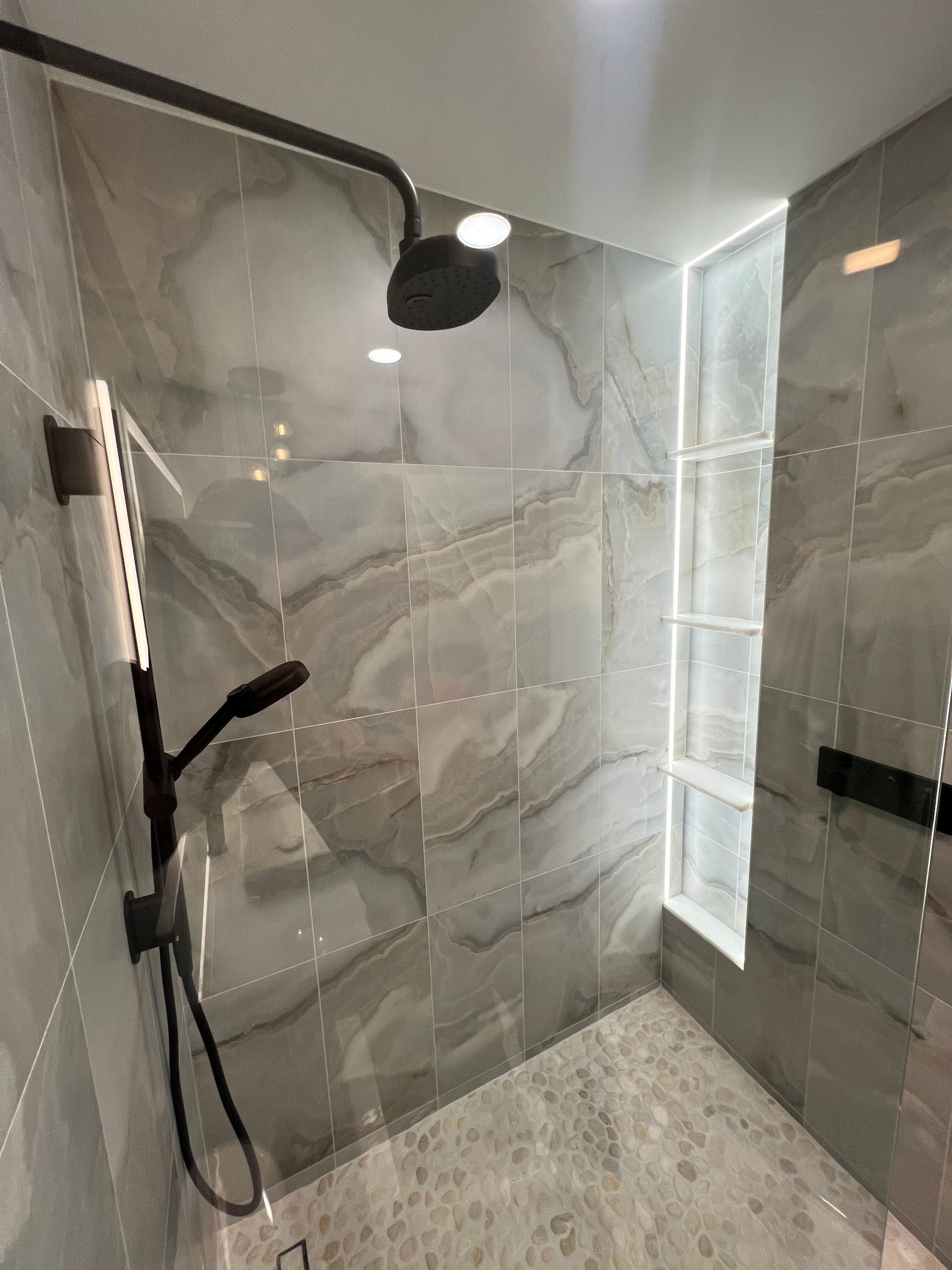 Modern tiled walk-in shower with glass enclosure and black shower fixture