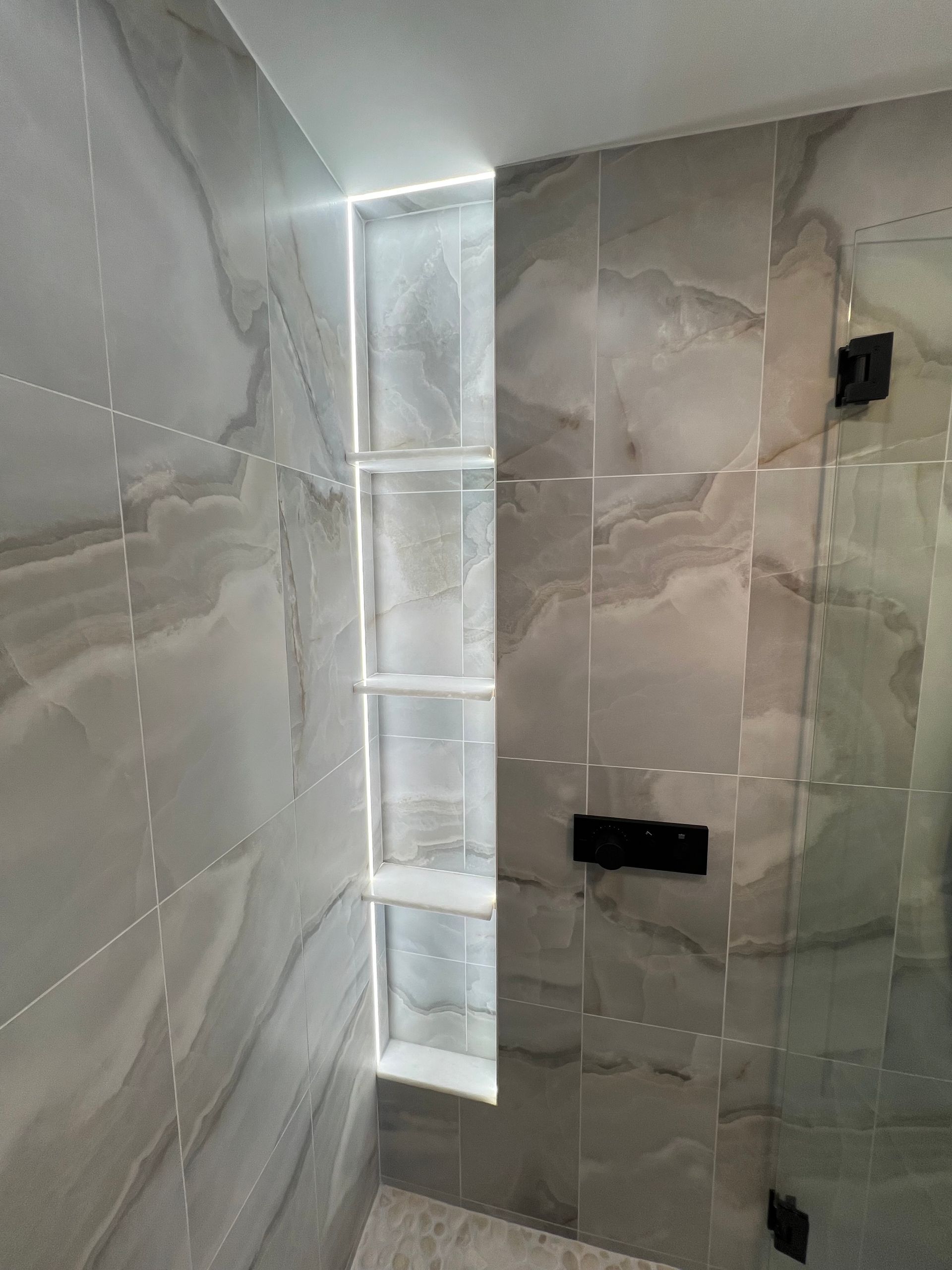 Modern tiled shower with a narrow frosted window and black fixtures