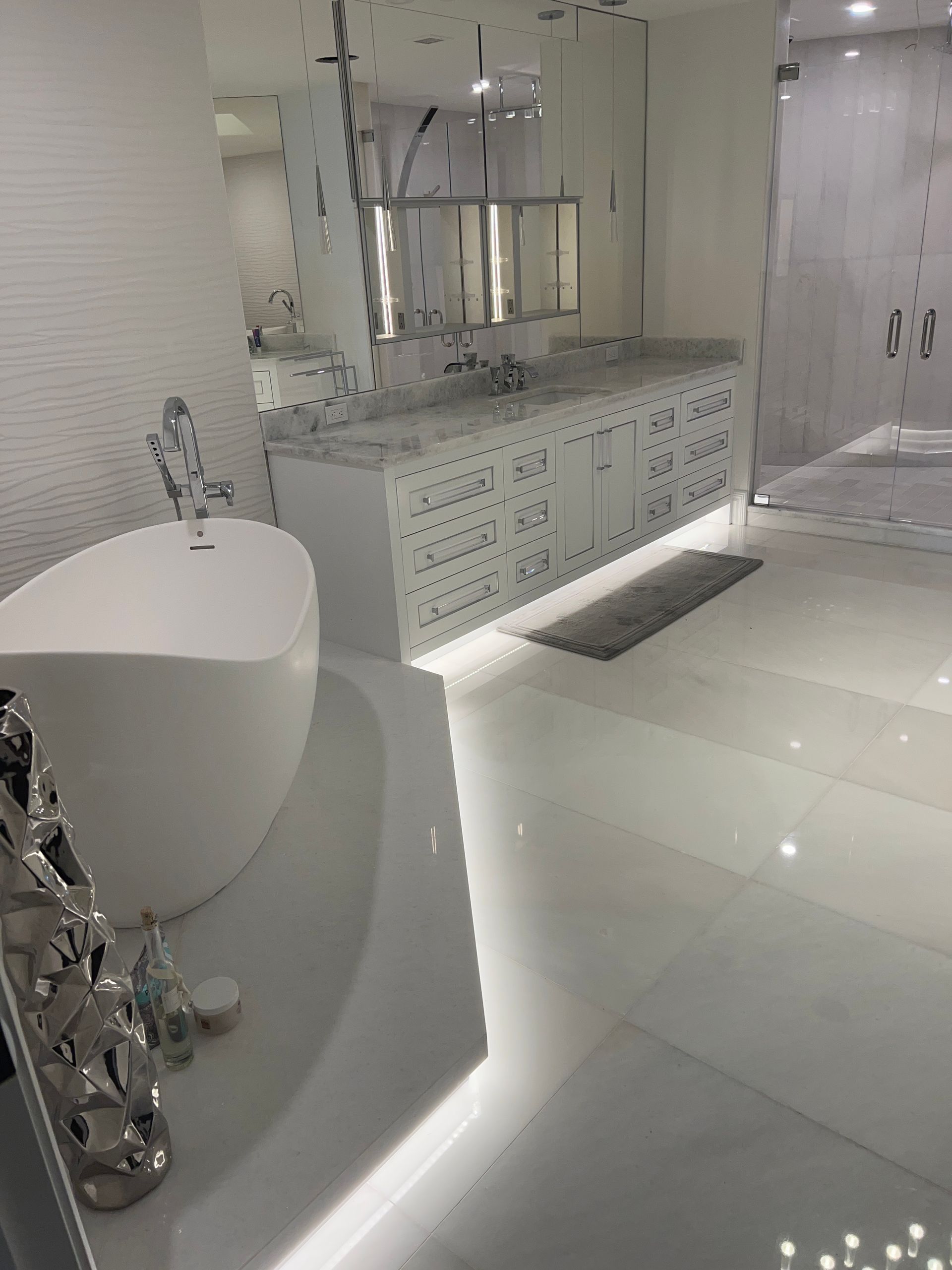 Bright white luxury bathroom with freestanding tub, double vanity, mirror, and tiled floor