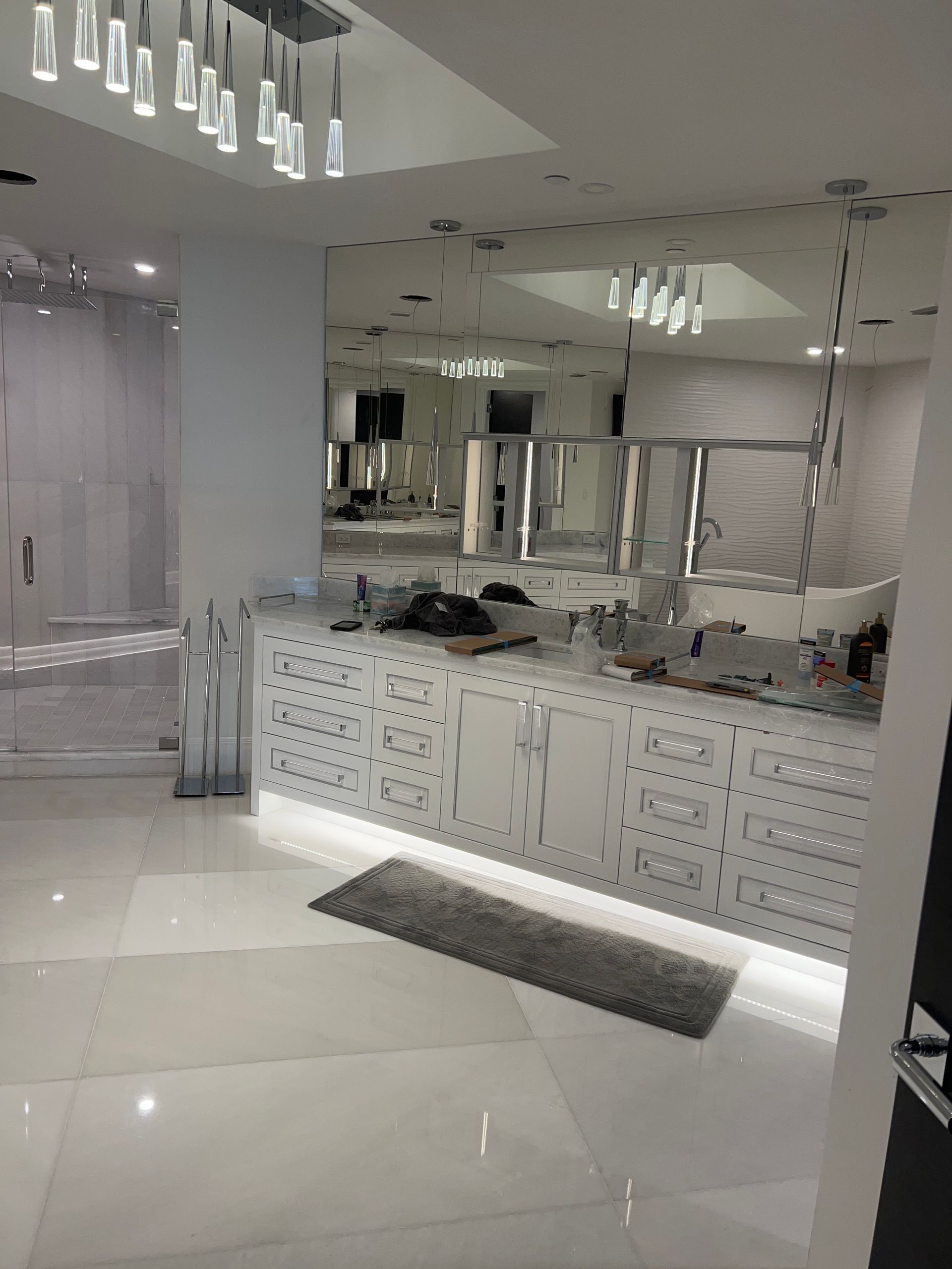 Bright, modern white lobby with glossy floors, mirrored walls, and a reception counter with patterned panels.