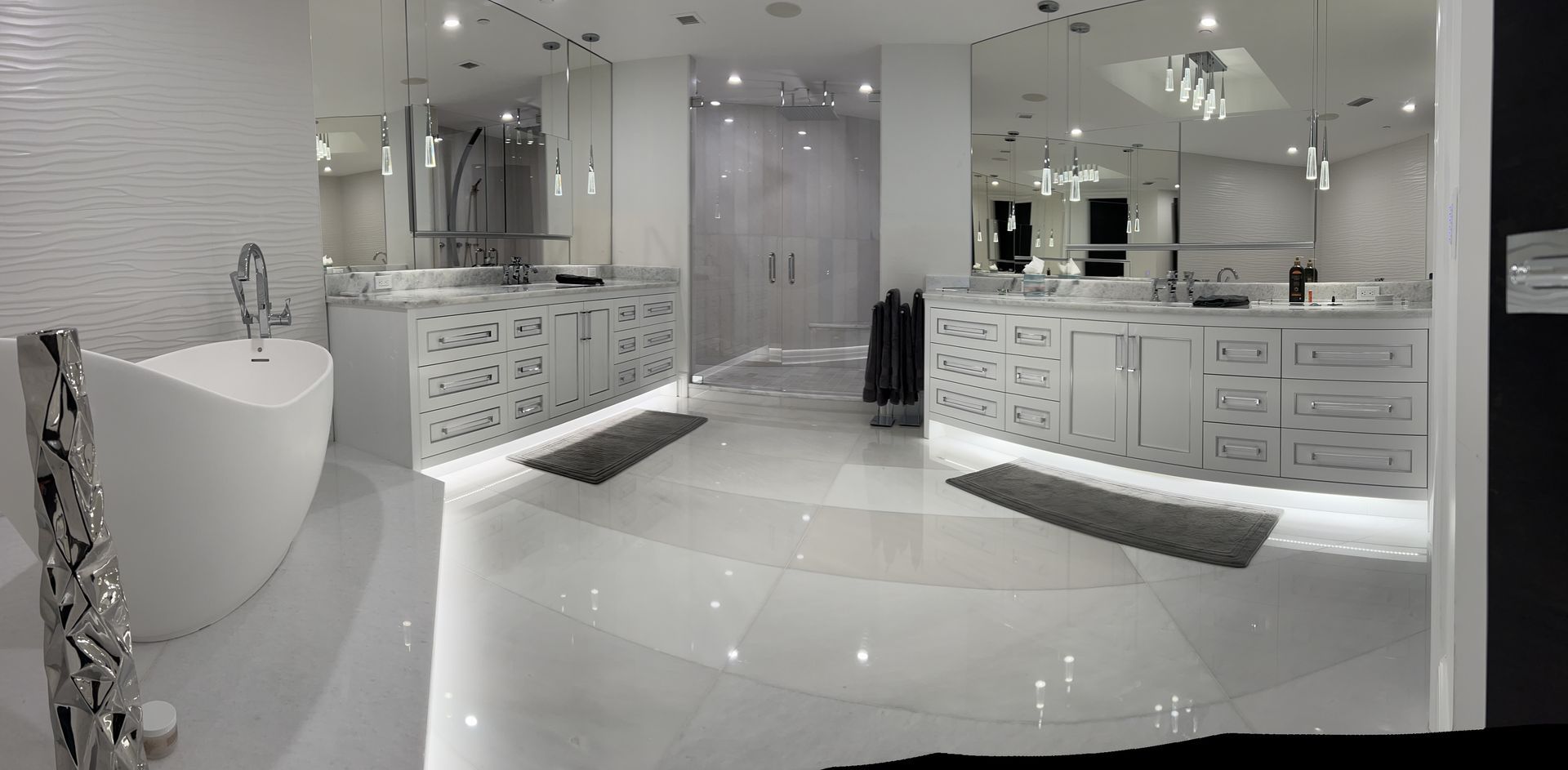 Bright white luxury bathroom with glossy tile, vanity, sink, and bathtub.