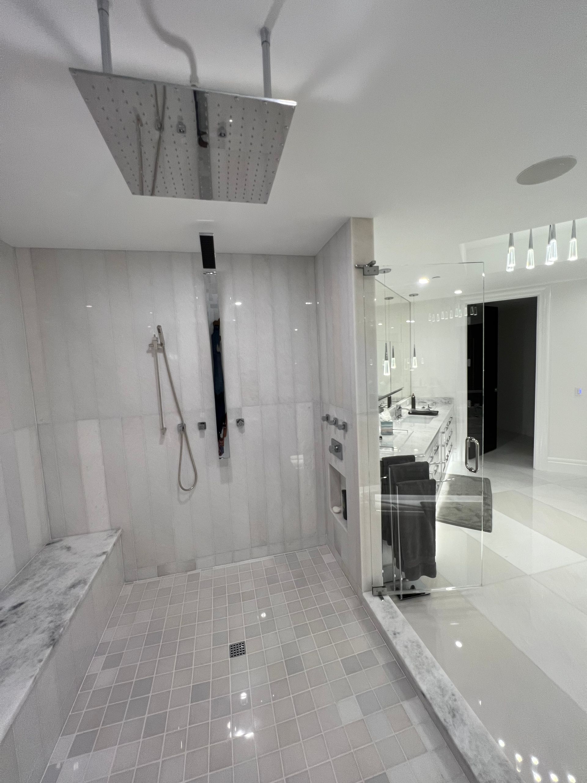 Modern white bathroom with a large walk-in shower and glossy tile floor