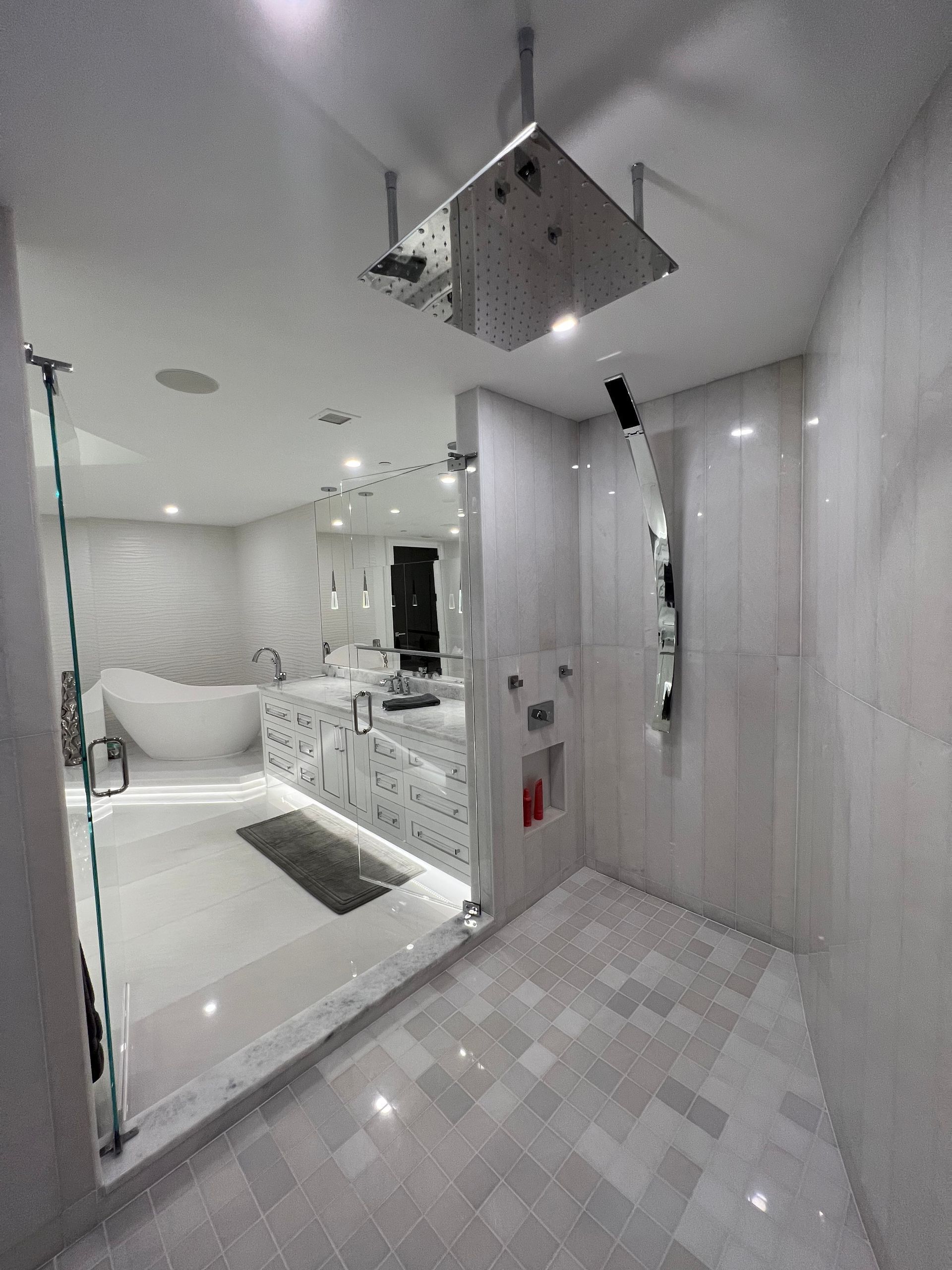 Bright white bathroom with mirrored vanity, glass shower, and square rainfall showerhead