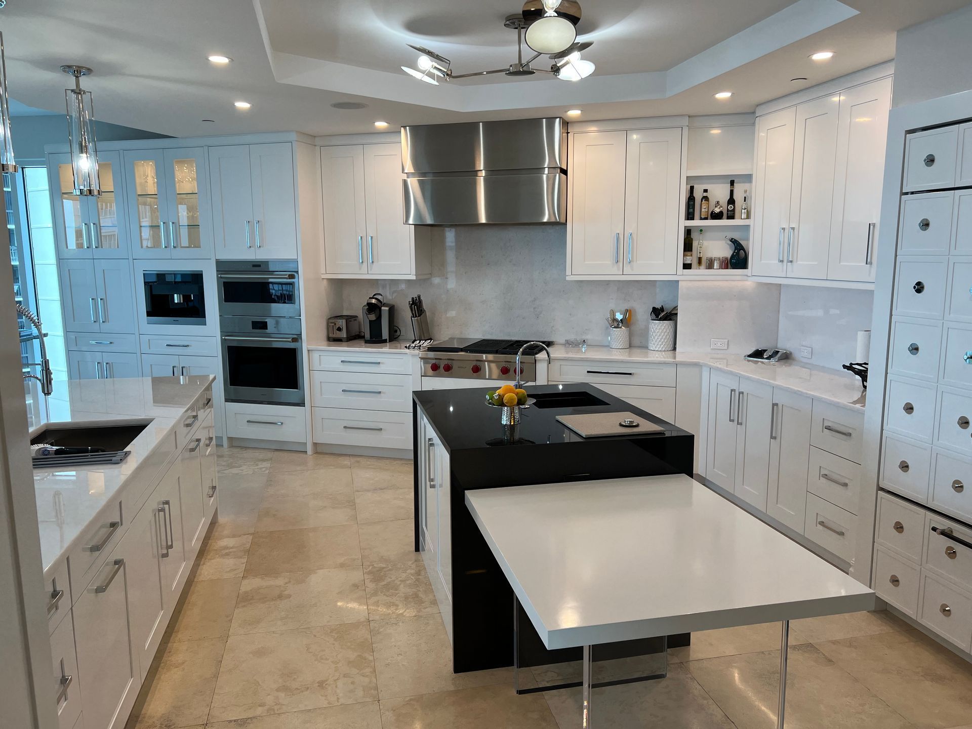 Bright white modern kitchen with black island, stainless appliances, and beige tile floor