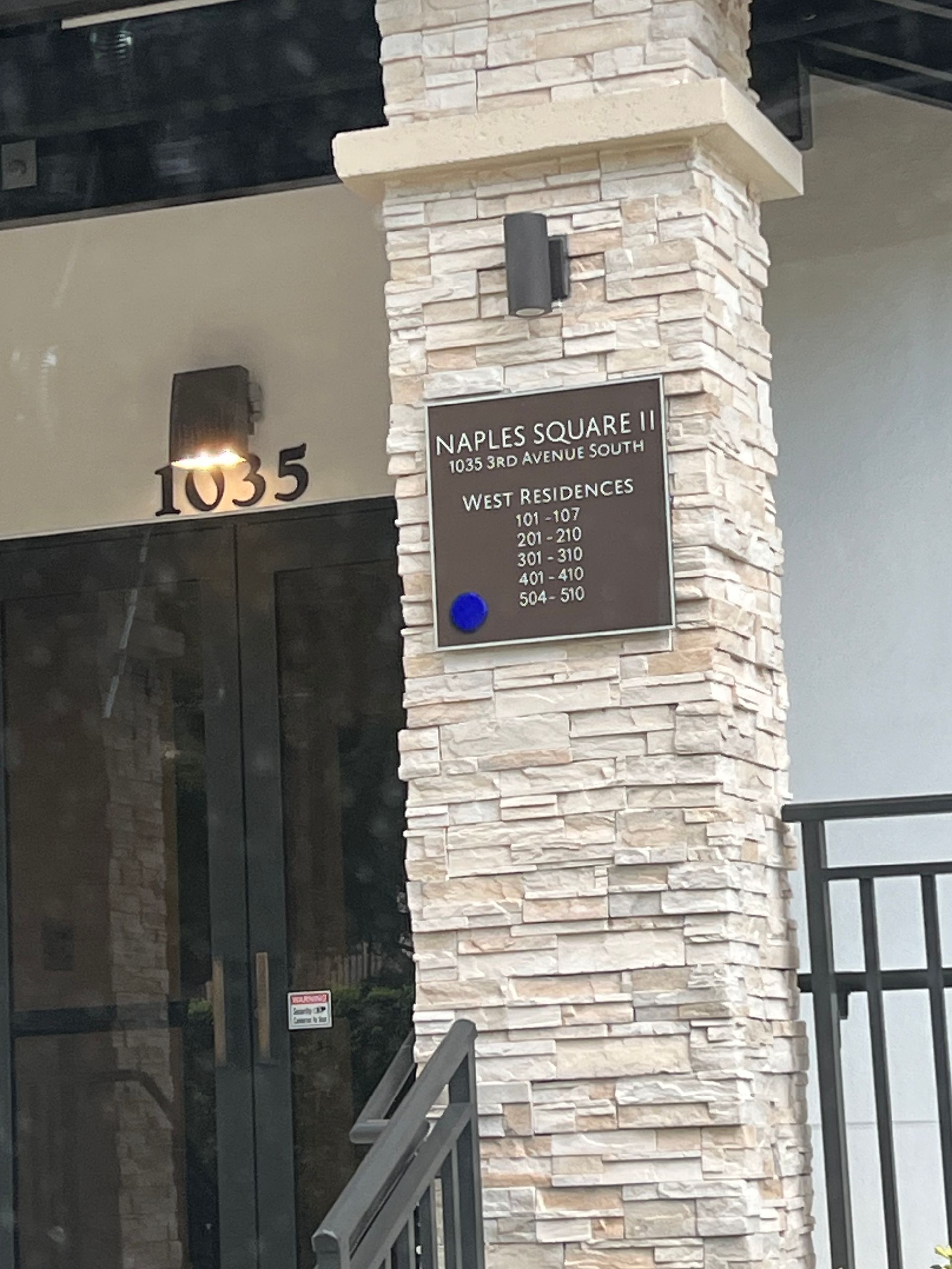 Building entrance with address 1035 and a black directory sign beside a stone column.