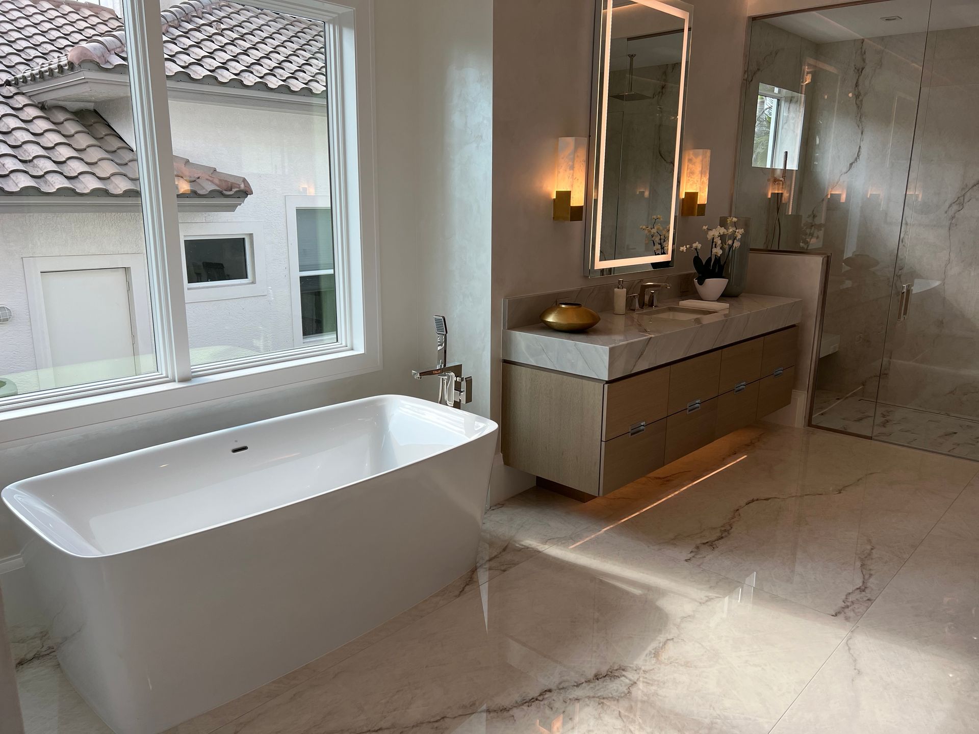 Modern bathroom with freestanding tub, double vanity, and large window overlooking rooftops