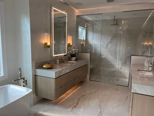 Modern bathroom with freestanding tub, double vanity, and glass shower in a marble finish