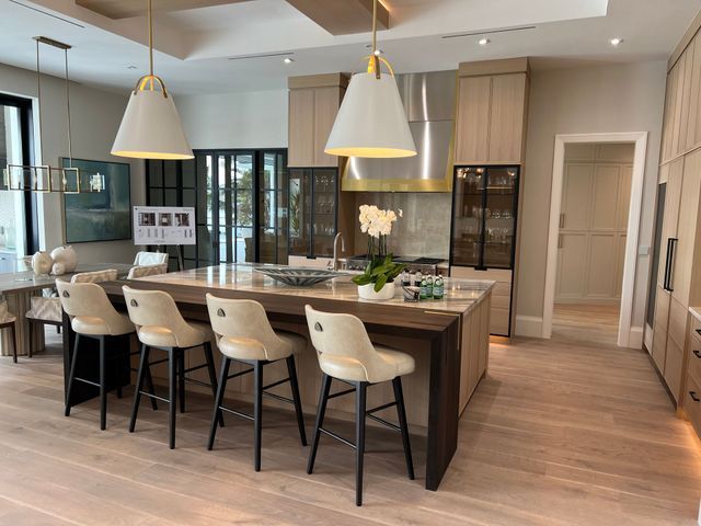 Modern kitchen with island, pendant lights, cream stools, and light wood finishes