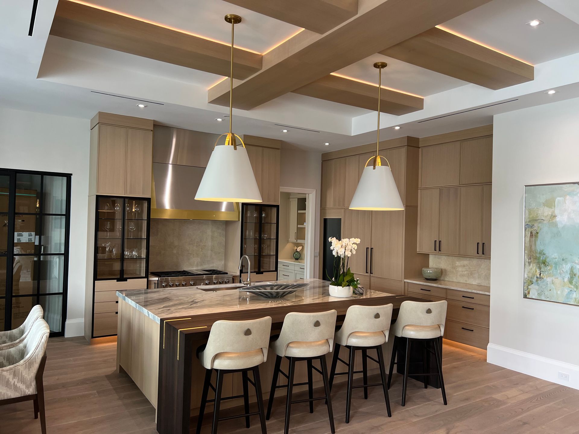 Modern kitchen with large island, pendant lights, bar stools, and wood cabinetry