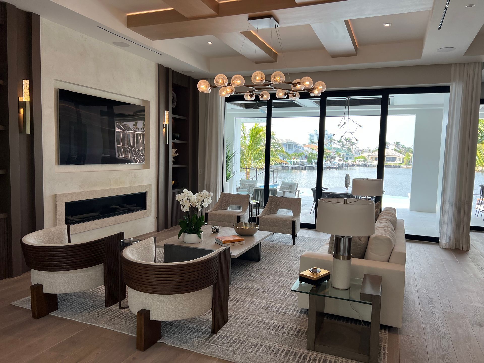Modern living room with white sofas, round chairs, fireplace, and ocean-view sliding doors