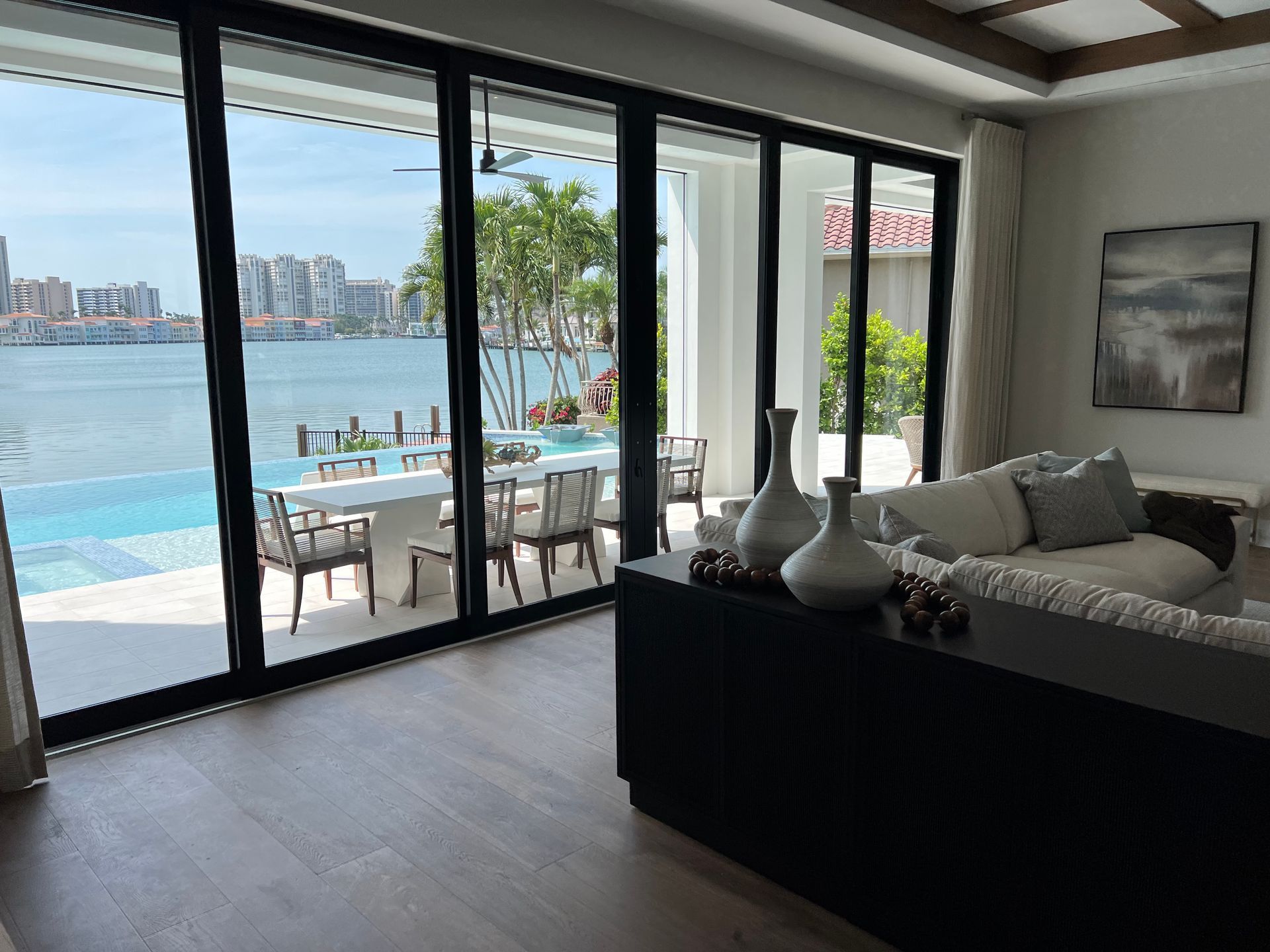 Luxury living room with sliding glass doors opening to a sunny pool and ocean view