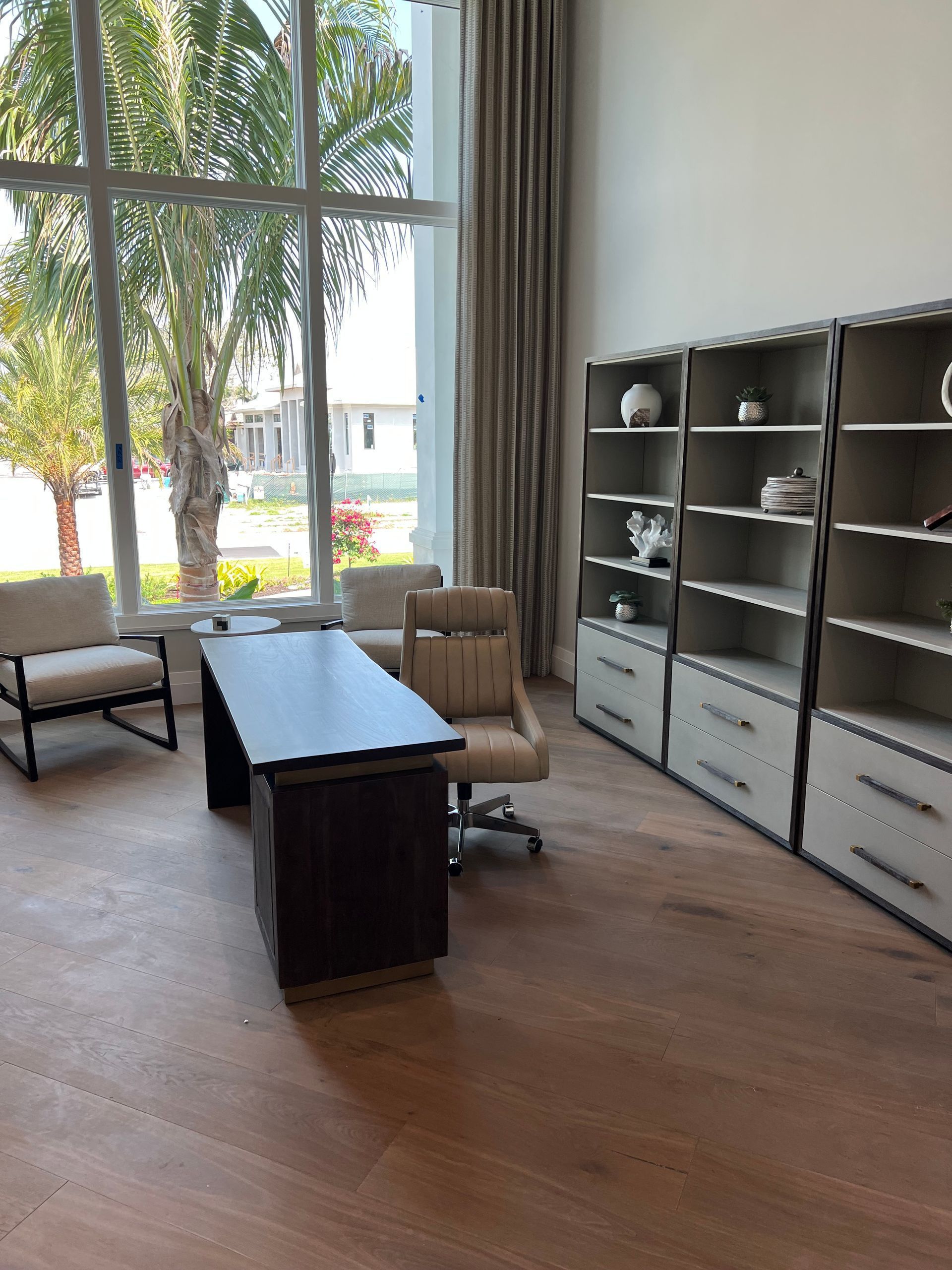 Modern living room with large windows, sofa, coffee table, and shelving unit