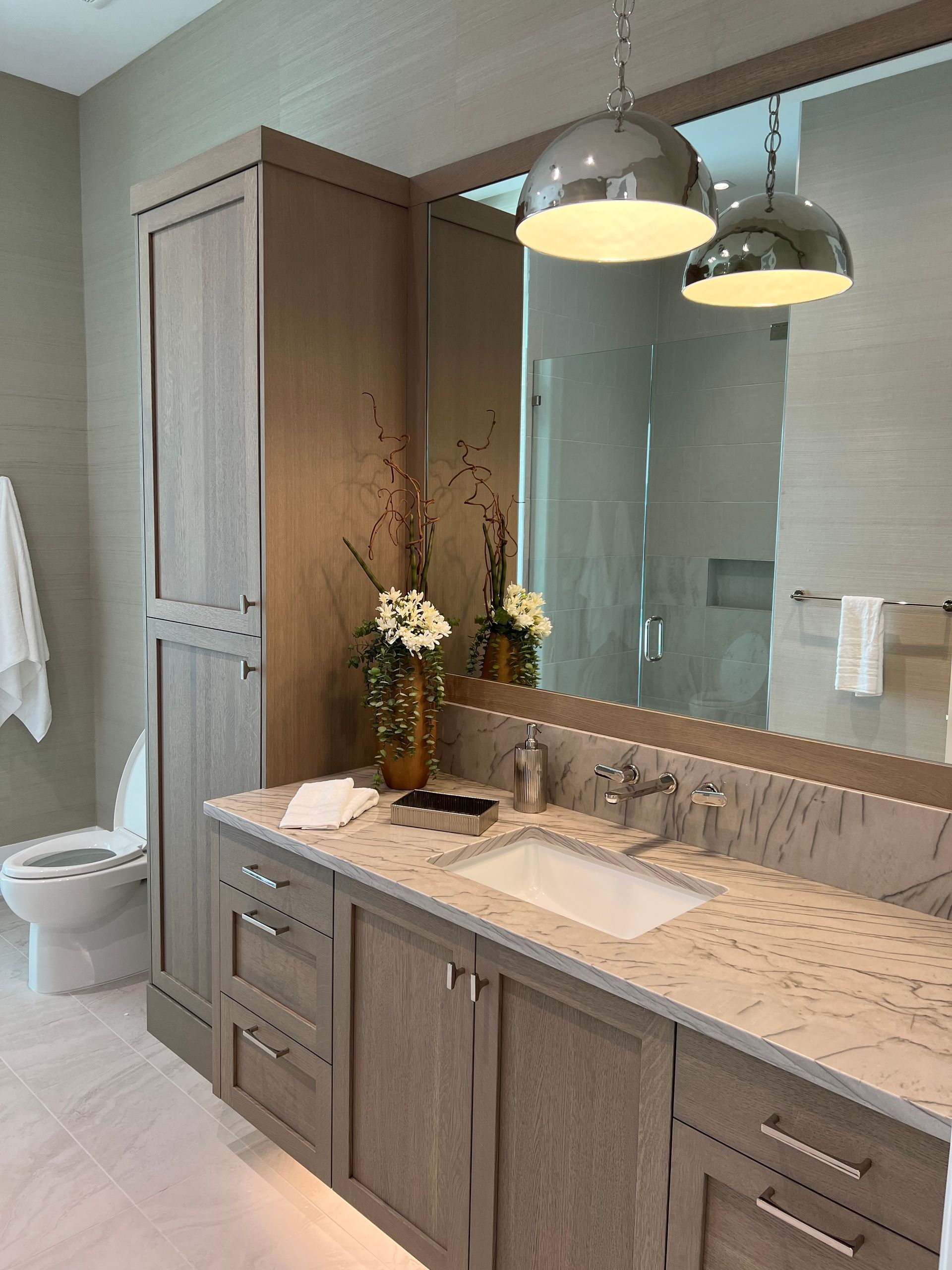Modern bathroom vanity with double sinks, mirror, pendant lights, and gray cabinetry