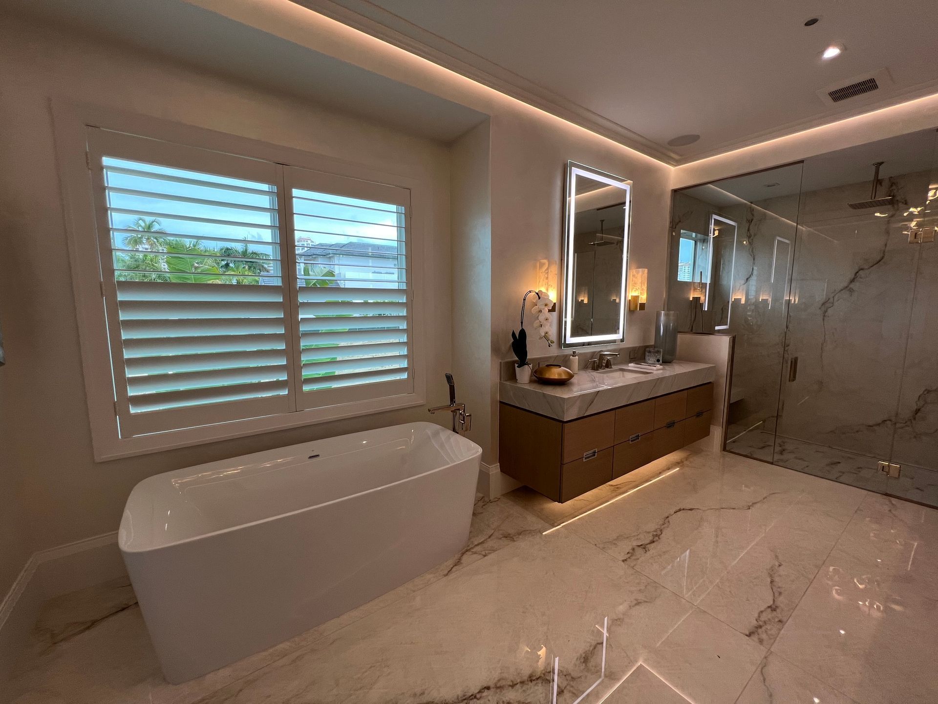 Modern bathroom with freestanding tub, double vanity, large mirror, and glass walk-in shower
