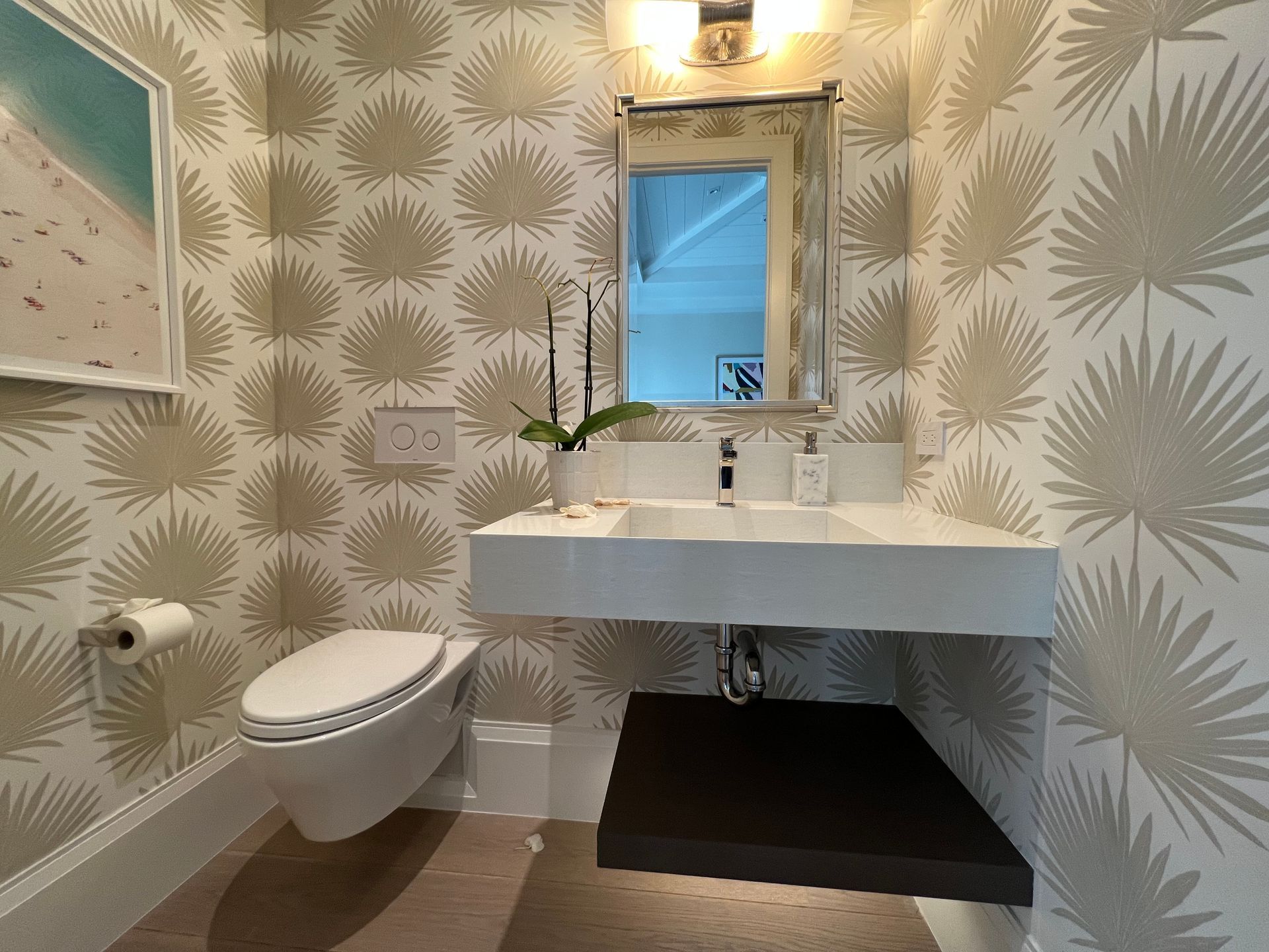 Small bathroom with patterned wallpaper, floating white sink, wall-mounted toilet, and mirror above the vanity.
