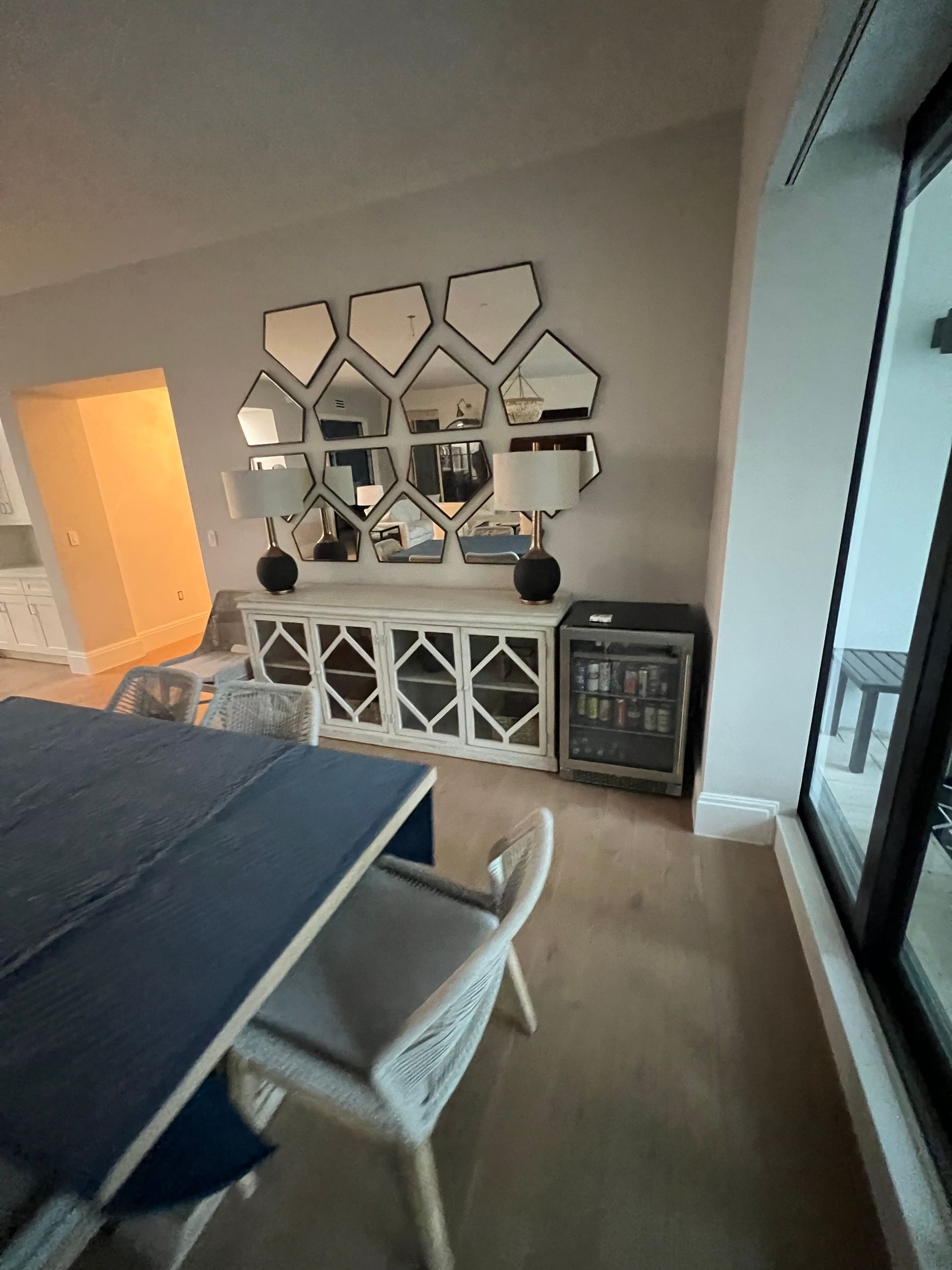 Dining room with a blue table, white chairs, and a mirrored sideboard against a wall.